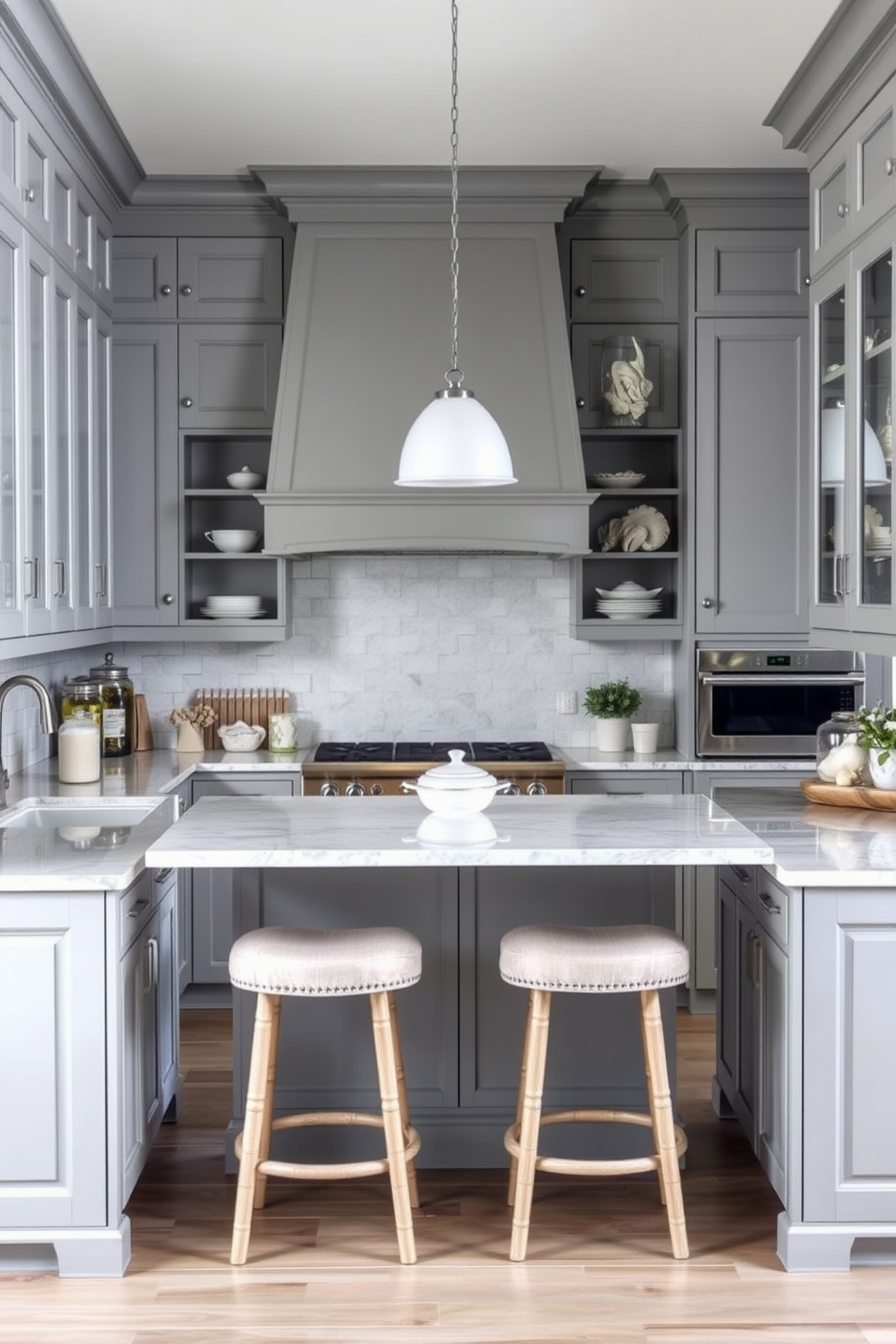 A coastal gray kitchen that embodies a relaxed beachy vibe. The cabinetry is a soft gray with whitewashed wood accents, complemented by a light quartz countertop that reflects the ocean's hues. Open shelving displays beach-themed decor and glass jars filled with seashells. A large island in the center features bar stools upholstered in a light fabric, creating a welcoming gathering space.