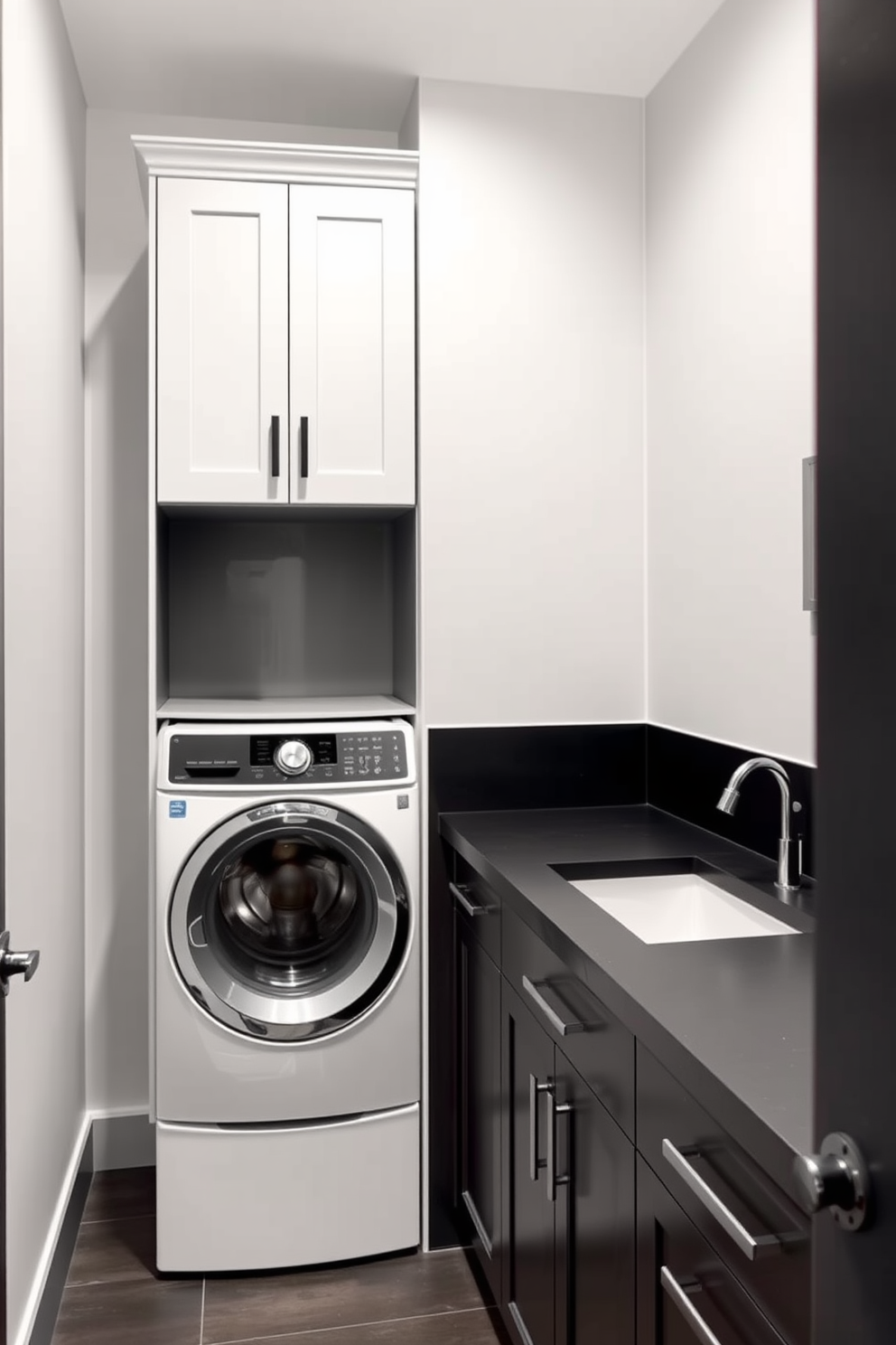 A modern laundry room featuring light gray walls complemented by dark cabinetry. The space includes a sleek washer and dryer stacked for efficiency, with a dark countertop providing ample folding space.