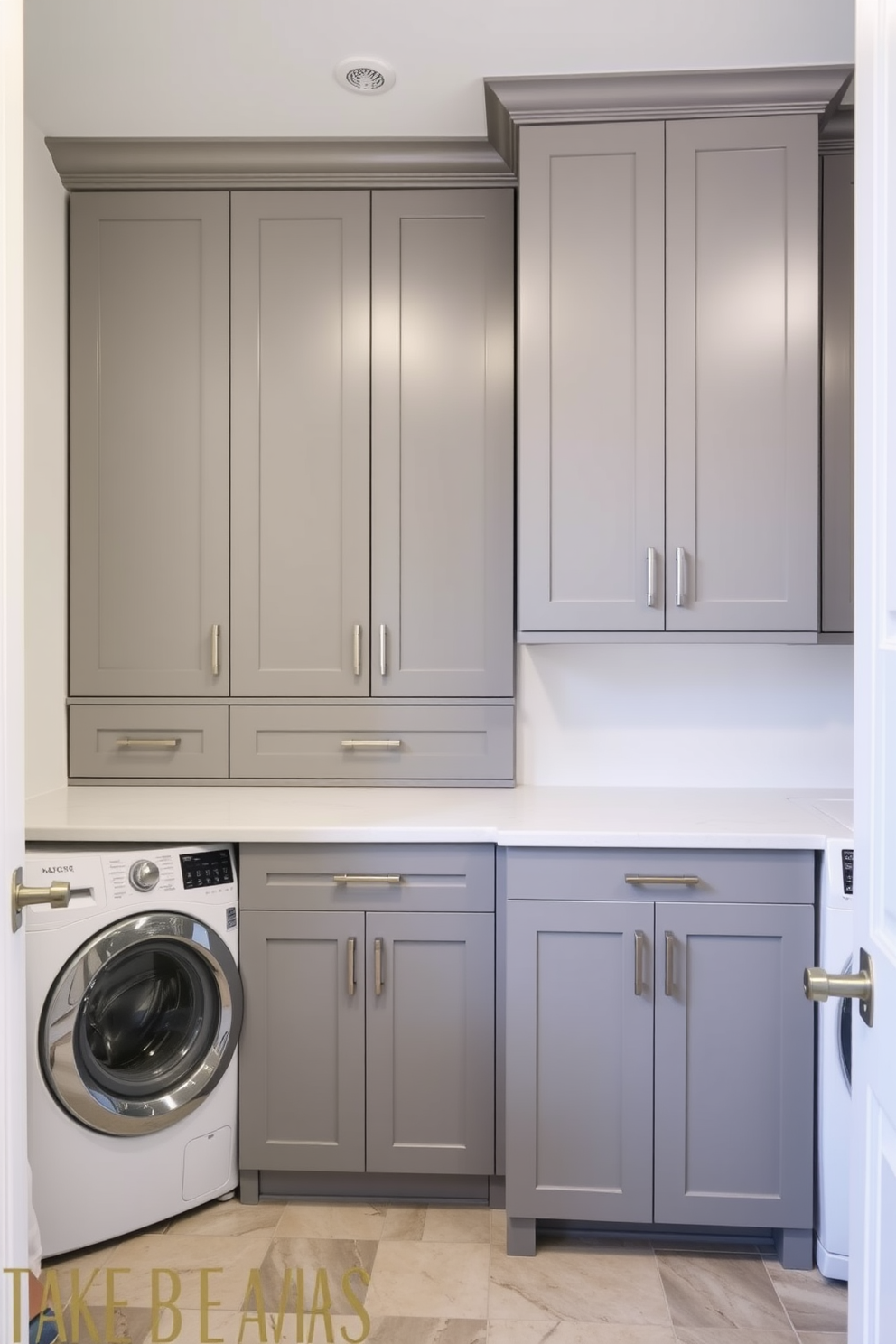 A modern laundry room featuring gray cabinetry with brushed nickel hardware. The cabinetry is sleek and minimalist, providing ample storage space while maintaining a clean aesthetic.