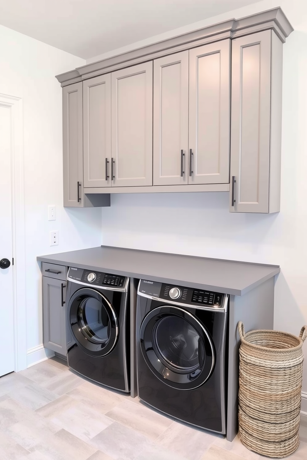 A stylish folding station with a sleek gray surface is the centerpiece of the laundry room. Surrounding it are custom cabinets in a matching gray tone, providing ample storage for laundry essentials. The walls are painted in a soft white hue, creating a bright and airy atmosphere. A modern washer and dryer sit side by side, complemented by a decorative laundry basket in a woven texture.