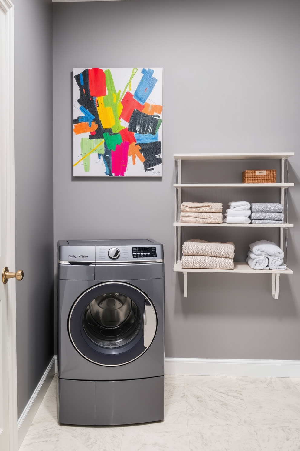 Bright artwork against gray walls. The room features a sleek gray laundry machine and dryer stacked for space efficiency. A large piece of colorful abstract art hangs prominently on the wall, adding vibrancy to the space. Decorative shelves hold neatly folded towels and laundry essentials, enhancing the room's functionality and style.