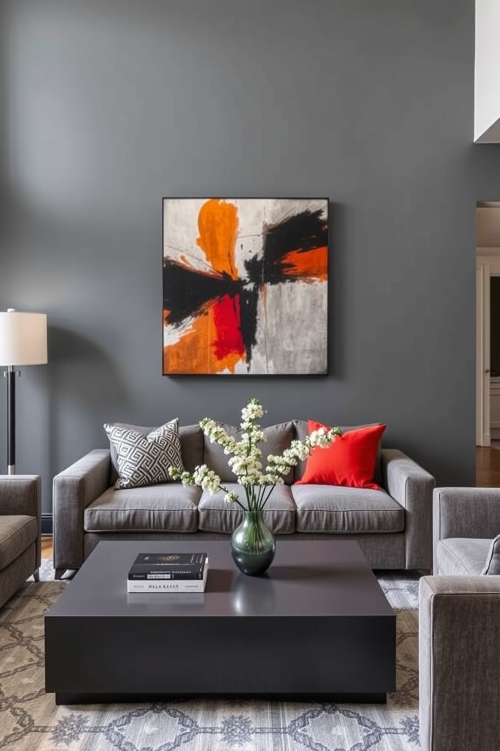 A bold gray accent wall serves as the focal point of the living room, adorned with a striking piece of contemporary artwork that adds a touch of sophistication. The room features plush gray sofas and a sleek coffee table, creating a cozy yet stylish atmosphere perfect for entertaining.