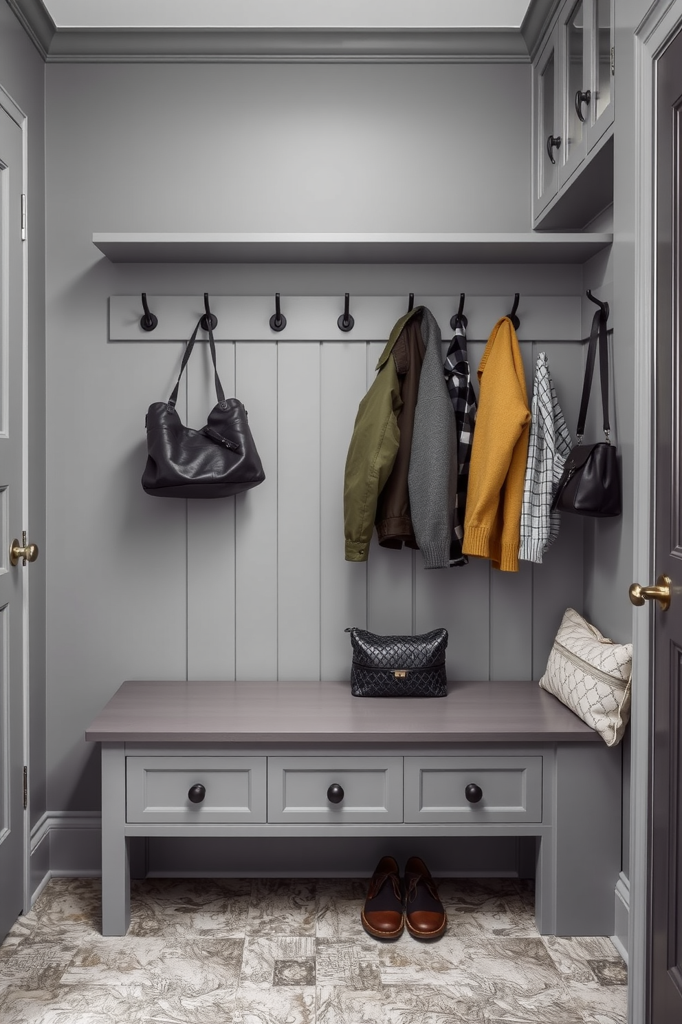 A stylish gray mudroom features a wall-mounted coat rack in a sleek gray finish, providing ample space for hanging jackets and bags. The floor is adorned with textured tiles that complement the gray tones, while a bench offers a convenient spot for putting on or taking off shoes.