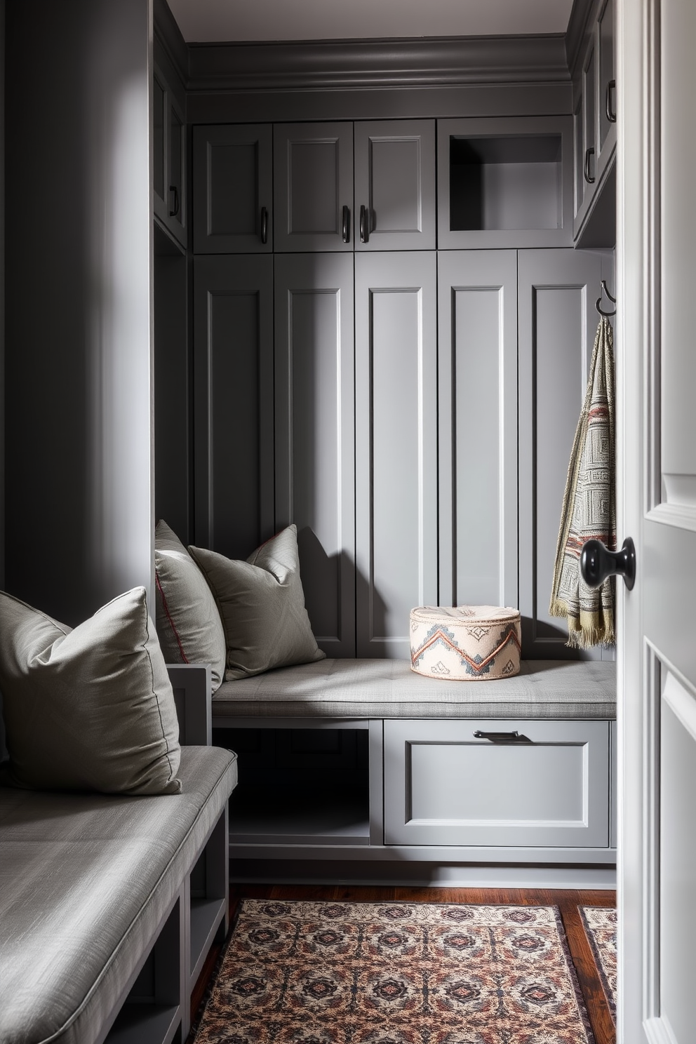 A luxurious gray upholstered seating option features plush cushions and elegant armrests. The fabric has a subtle sheen, adding sophistication to any space. The gray mudroom design incorporates built-in storage with sleek cabinetry and a bench for convenience. A patterned rug complements the neutral tones, creating a welcoming atmosphere.