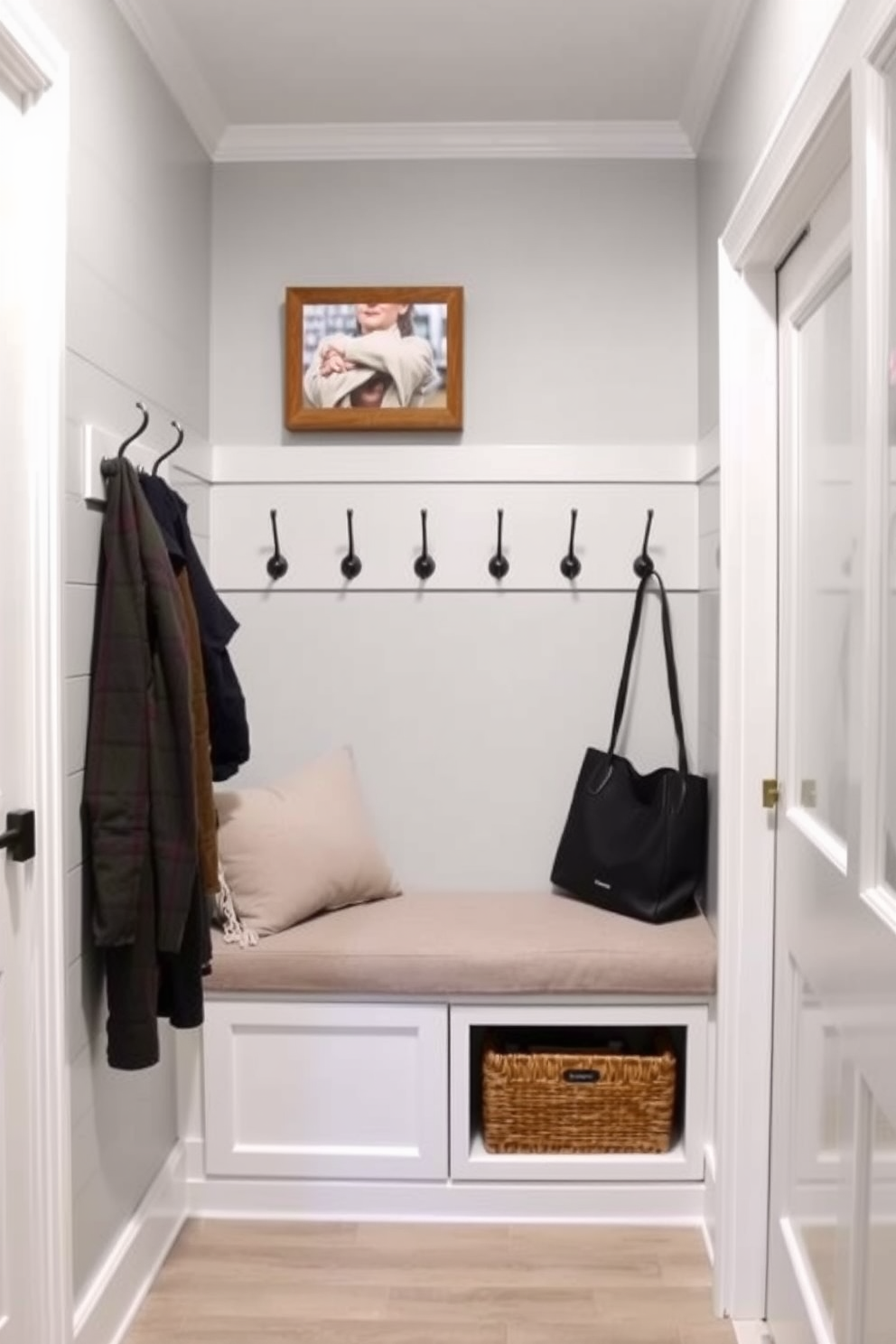 Light gray shiplap walls create a warm and inviting atmosphere in the mudroom. The space features a built-in bench with plush cushions, complemented by hooks for hanging coats and bags.