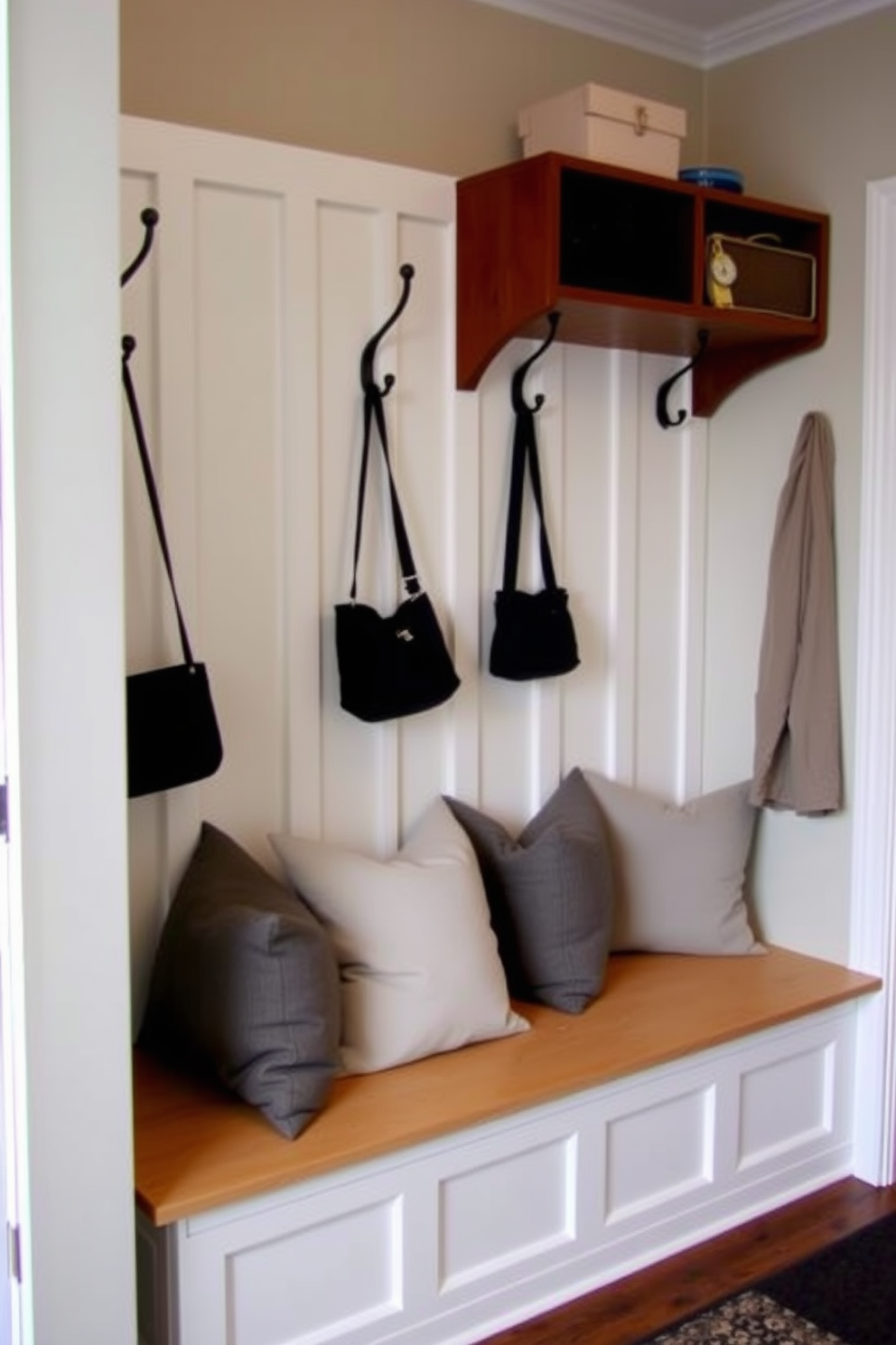 A cozy mudroom featuring a built-in bench adorned with soft gray cushions. The walls are painted in a light, airy color, complemented by stylish hooks for coats and bags.