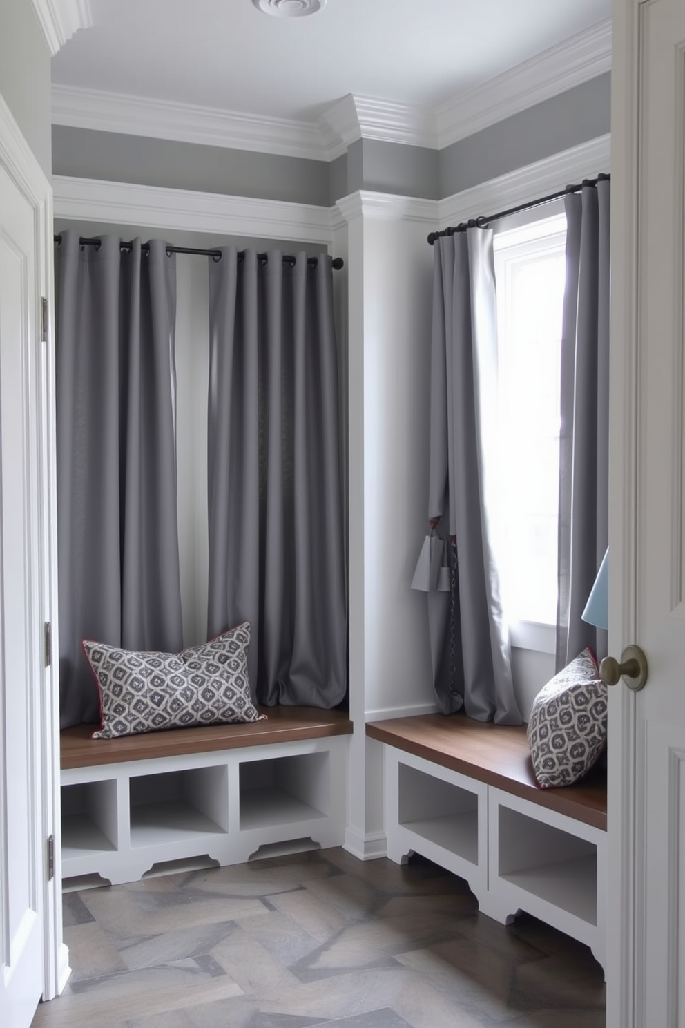 A warm gray mudroom filled with natural light. The space features a built-in bench with soft cushions and hooks for coats above. Light gray cabinetry lines the walls, complemented by a sleek white countertop. Large windows allow sunlight to stream in, illuminating the textured stone floor.