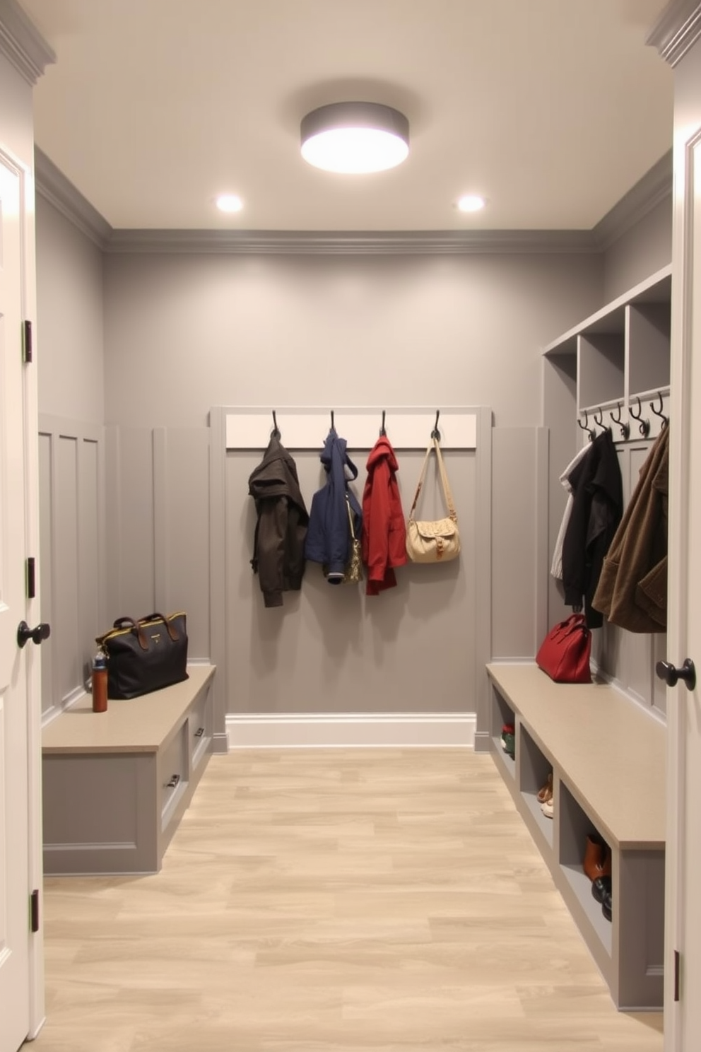 Bright lighting fixtures illuminate the spacious gray mudroom, enhancing its functionality and aesthetic appeal. The room features built-in storage benches with hooks above for coats and bags, creating an organized and welcoming entryway.