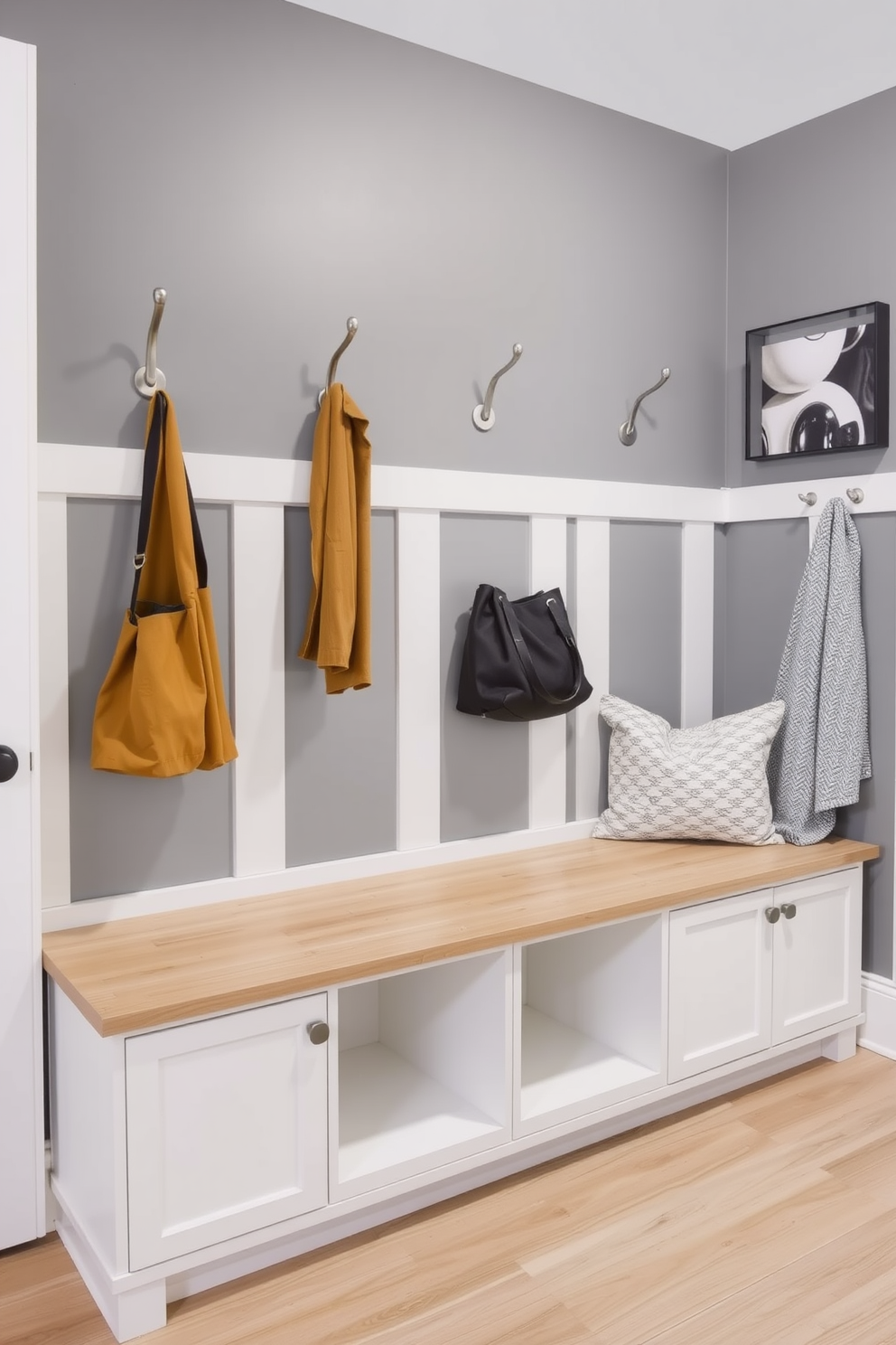 A stylish mudroom featuring a gray accent wall adorned with sleek hooks for hanging coats and bags. The space is designed with a practical bench for seating and storage, complemented by a durable floor in a light wood finish.