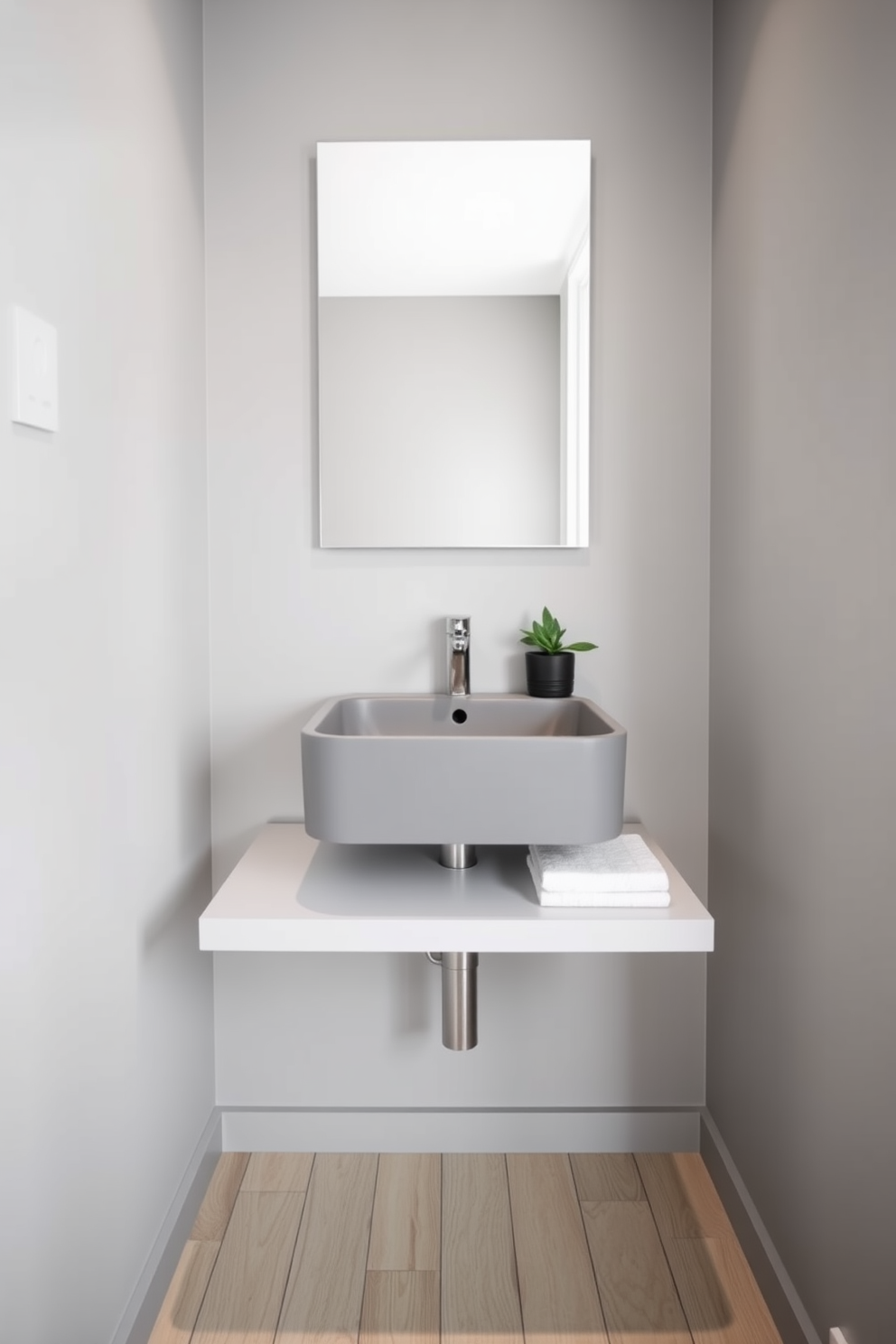 A minimalist gray sink is mounted on a sleek floating shelf, creating a clean and modern aesthetic. The walls are painted in a soft gray tone, complementing the simplicity of the design while providing a serene atmosphere. The floor features light wood planks that add warmth to the space, enhancing the minimalist vibe. A small potted plant sits on the floating shelf, adding a touch of greenery and life to the powder room.