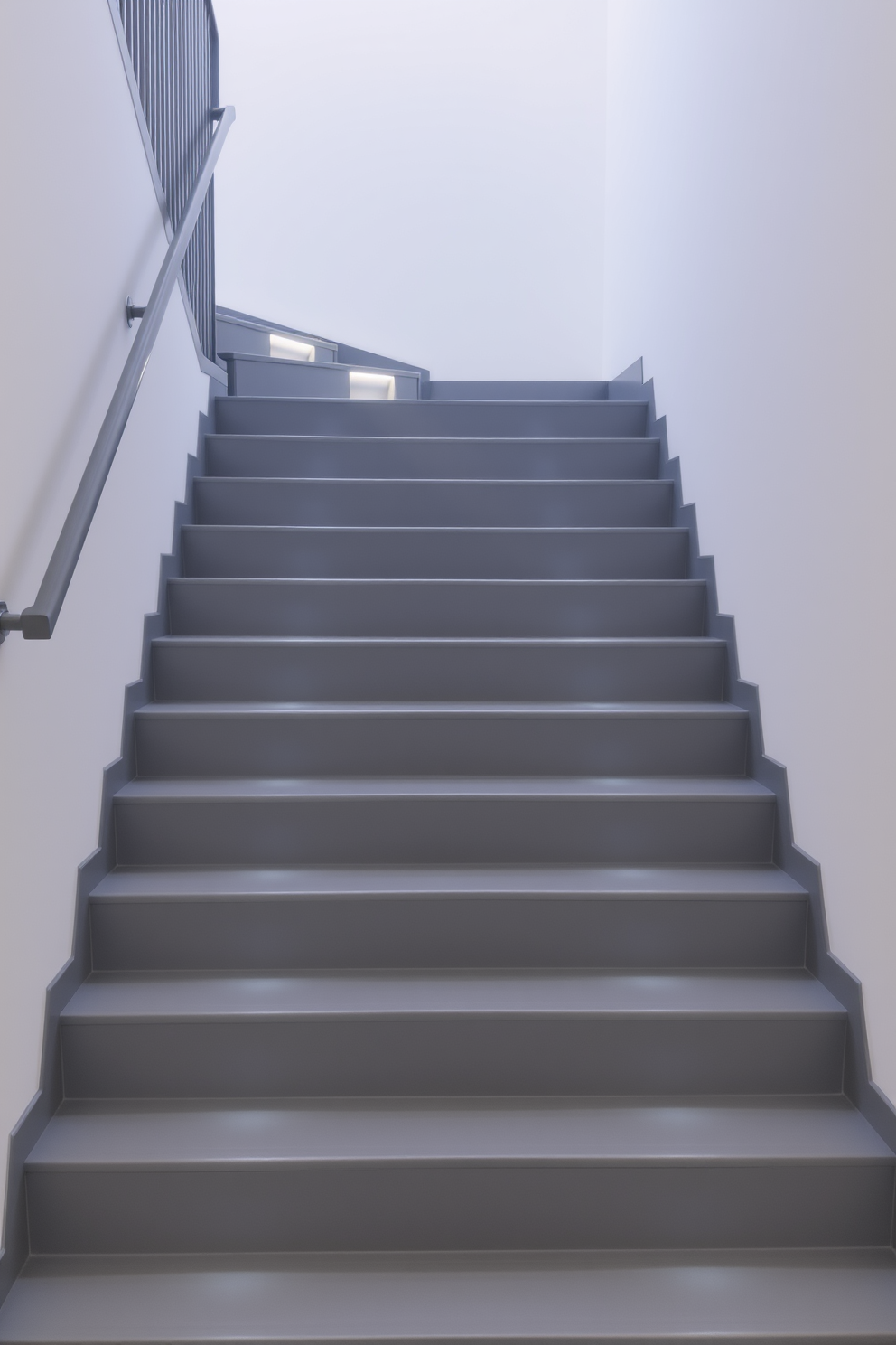 A minimalist gray staircase features sleek, straight lines with a smooth finish that exudes modern elegance. Subtle LED lighting is integrated into the steps, casting a soft glow that highlights the staircase's architectural beauty. The walls surrounding the staircase are painted in a crisp white, creating a striking contrast with the gray tones. A simple yet stylish handrail complements the design, enhancing both safety and aesthetic appeal.