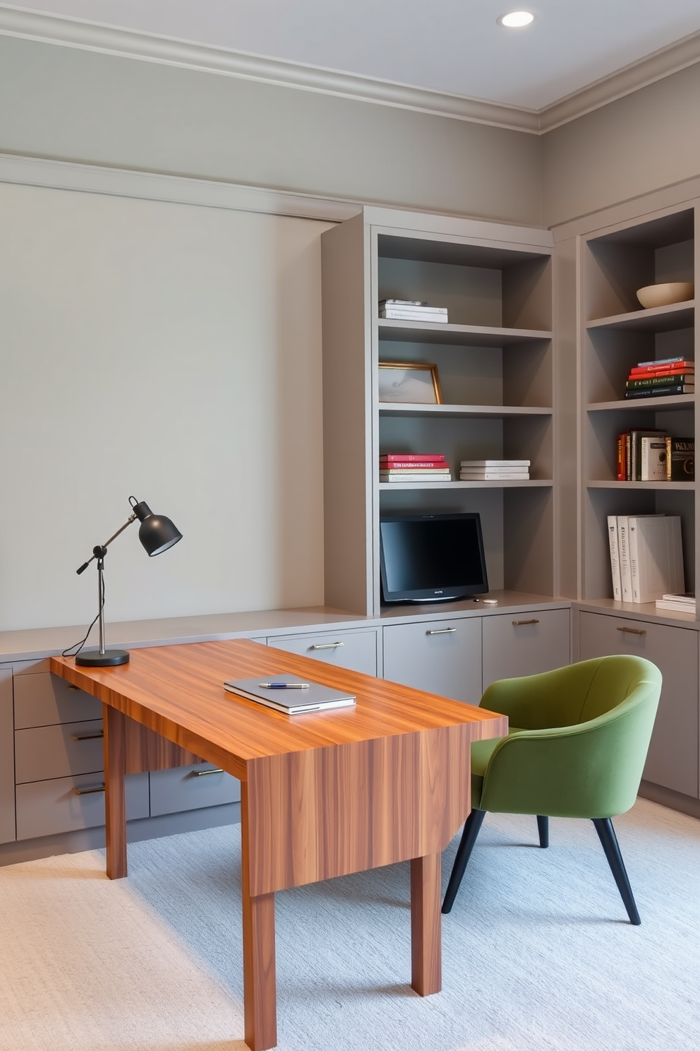 A modern home office featuring a sleek wooden desk positioned against a wall with built-in shelves. The room is painted in a soft gray tone, and a green accent chair is placed beside the desk to provide additional seating options.