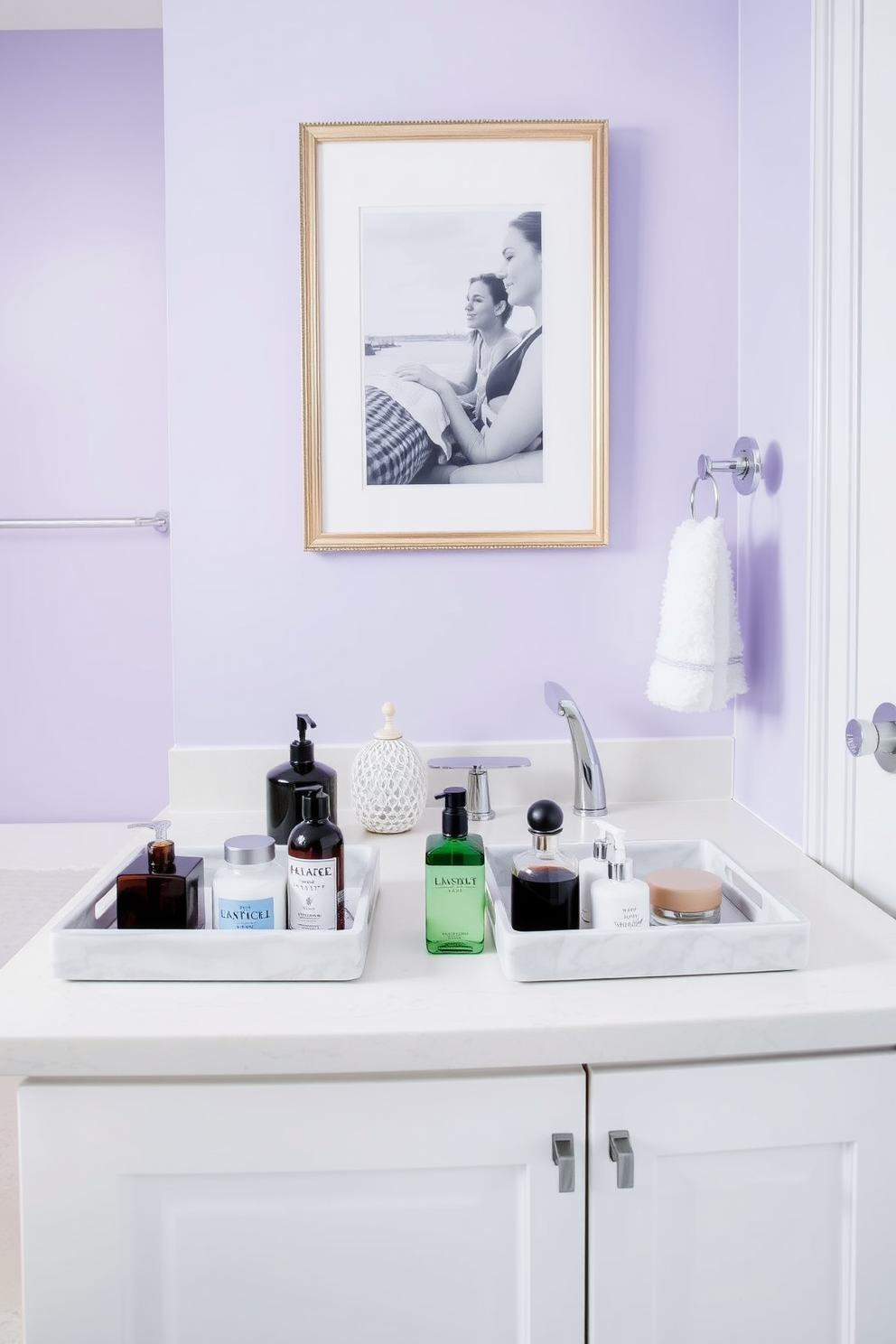 A stylish guest bathroom featuring decorative trays for toiletries arranged on a sleek countertop. The trays are crafted from ceramic with a glossy finish and hold an assortment of elegant bottles and jars. The walls are painted in a soft lavender hue, complementing the white cabinetry and polished chrome fixtures. A plush white rug lies underfoot, adding warmth to the space while a framed artwork hangs above the vanity, enhancing the overall aesthetic.