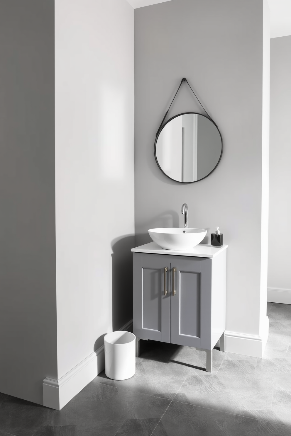 A sleek half bath featuring a monochromatic color scheme that emphasizes modern elegance. The walls are painted in a soft gray, complemented by a matching vanity with a minimalist design and a white vessel sink. The floor showcases large gray tiles with a matte finish, creating a seamless look. A stylish round mirror with a thin black frame hangs above the sink, reflecting the understated sophistication of the space.