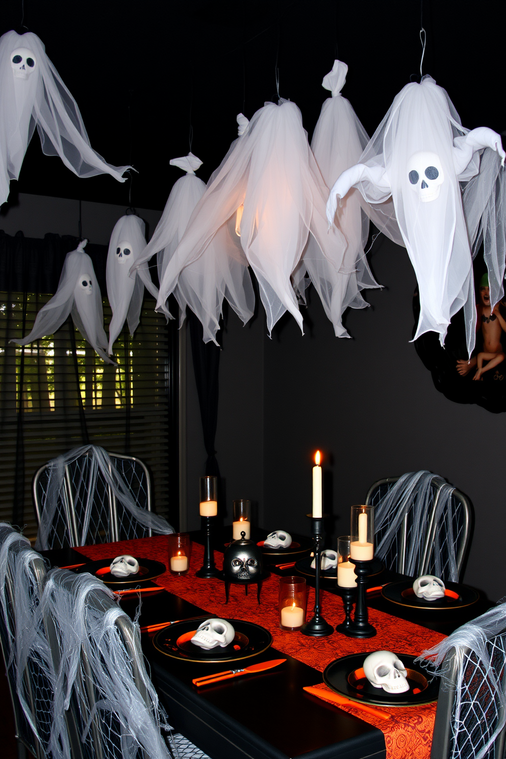 A Halloween-themed dining room featuring mood lighting created by dimmed pendant lights hanging above a rustic wooden table. The table is adorned with black and orange tableware, and a centerpiece of carved pumpkins adds a festive touch.