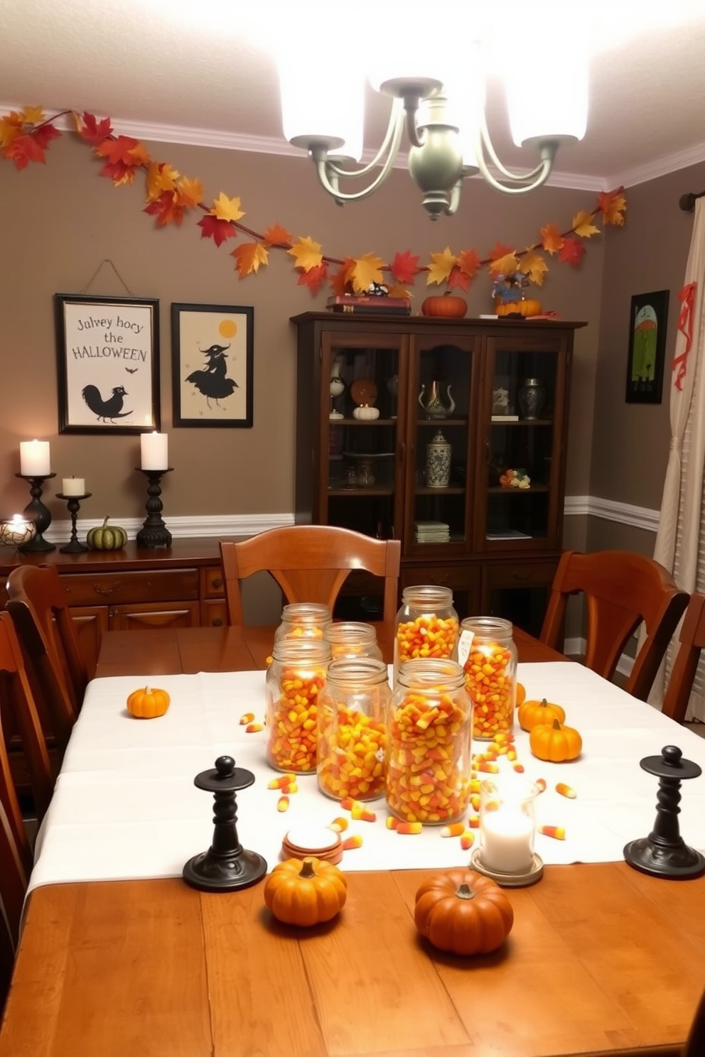 A festive dining room setting for Halloween featuring a wooden dining table adorned with a white tablecloth. Centered on the table are several mason jars filled with colorful candy corn, surrounded by small decorative pumpkins and flickering candle holders. The walls are decorated with whimsical Halloween-themed artwork and garlands made of autumn leaves. Soft, ambient lighting creates a warm atmosphere, perfect for a cozy gathering with family and friends.