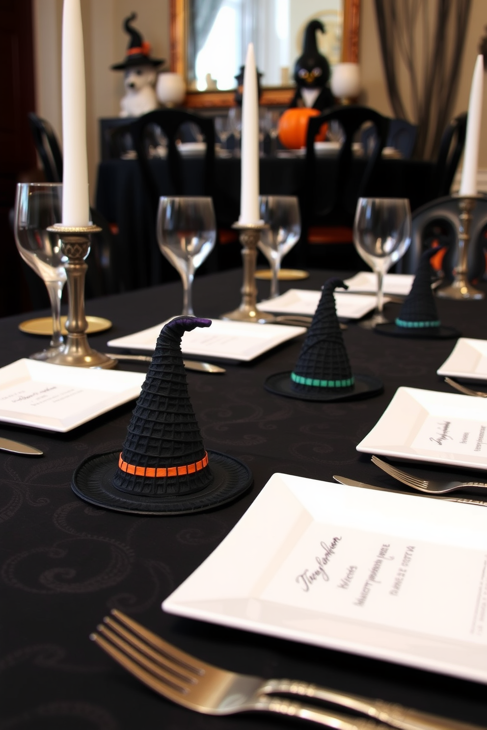 A Halloween dining room setting featuring elegantly designed witch hat place cards for each guest. The table is adorned with a black tablecloth, and the place cards are crafted from textured black paper topped with miniature witch hats in vibrant colors.