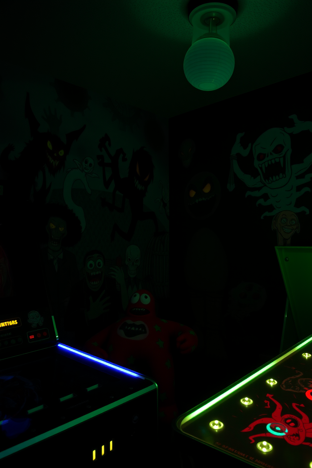 A spooky game room featuring shelves adorned with intricately designed skeleton figurines in various poses. The walls are painted in deep purple, and colorful LED lights create an eerie ambiance, highlighting the playful Halloween decorations throughout the space.