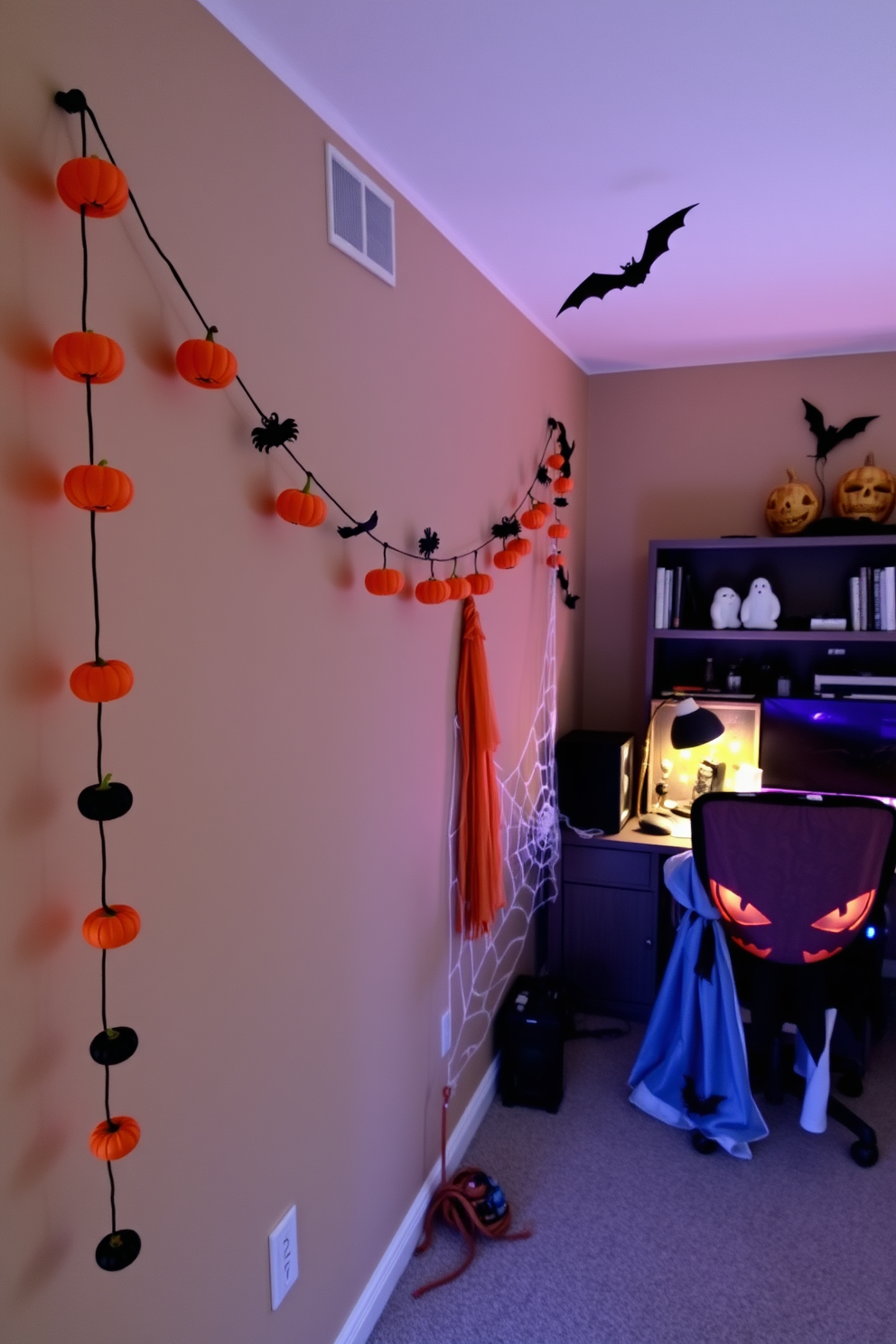 A whimsical Halloween garland stretches across the wall, adorned with miniature pumpkins, ghosts, and bats. The vibrant colors of orange, black, and purple create a festive atmosphere in the space. The home office is decorated with playful Halloween accents, including a spiderweb draped over the desk and a spooky-themed chair cover. Soft lighting illuminates the area, enhancing the cozy yet eerie vibe perfect for the season.