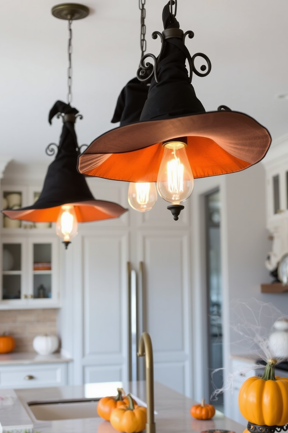 Witch hats are suspended from elegant light fixtures, adding a whimsical touch to the kitchen. The space is adorned with subtle Halloween decorations, featuring pumpkins and cobweb accents that create a festive atmosphere.