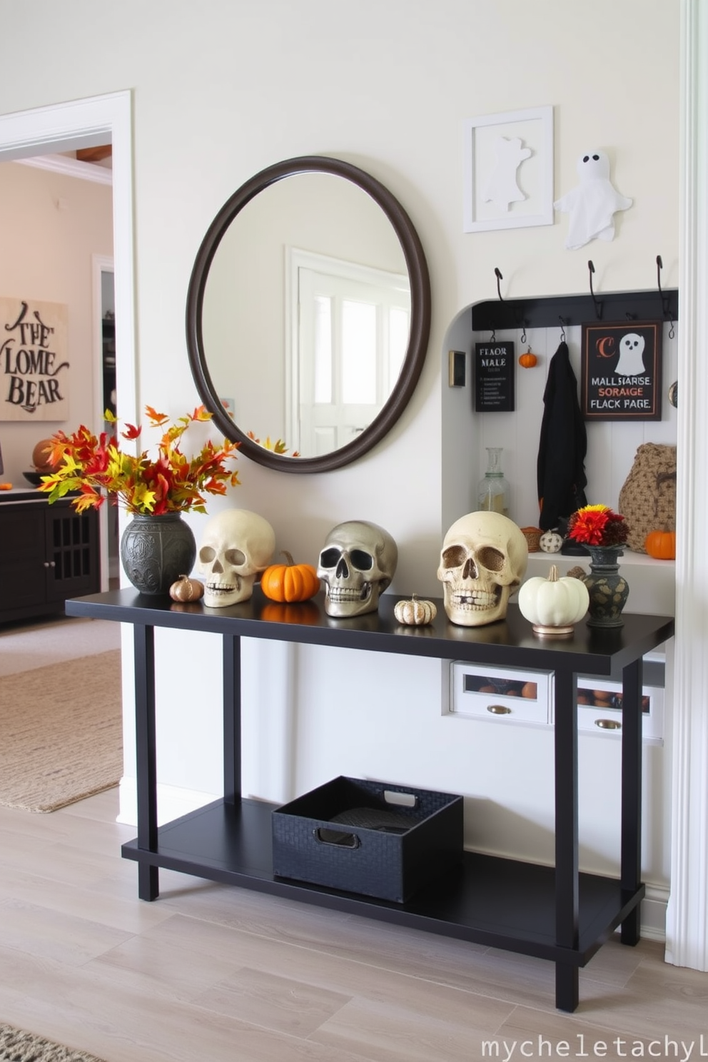 A stylish entry table adorned with decorative skulls in various sizes and finishes. The table is complemented by a backdrop of autumn-themed decor, featuring small pumpkins and vibrant fall foliage. In the adjacent mudroom, a cohesive Halloween theme is created with spooky wall art and playful ghost decorations. The space is functional yet festive, incorporating storage solutions that blend seamlessly with the seasonal decor.