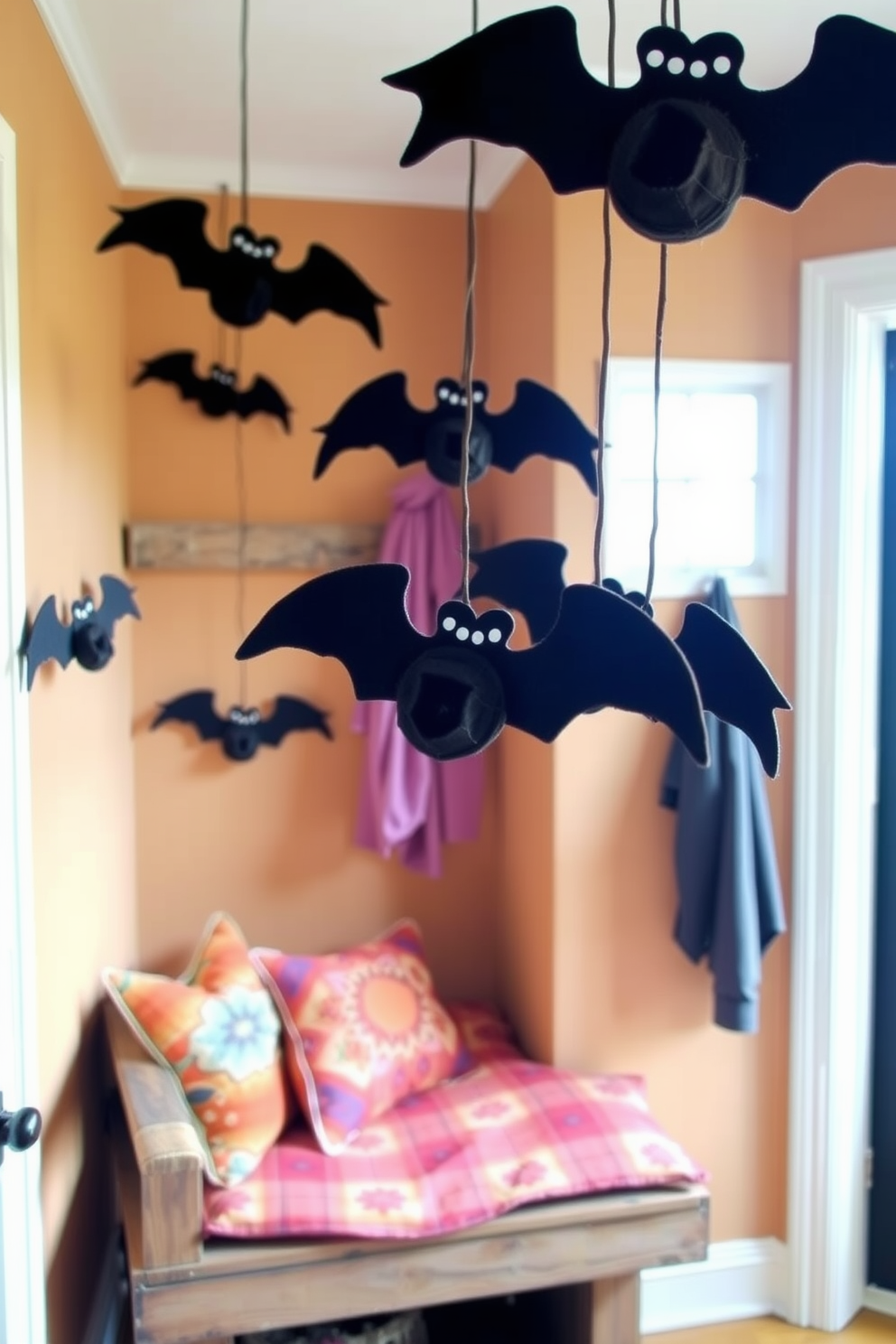 A cozy mudroom decorated for Halloween features hanging felt bats suspended from the ceiling. The walls are painted in a warm neutral tone, and a rustic bench with colorful cushions provides seating.