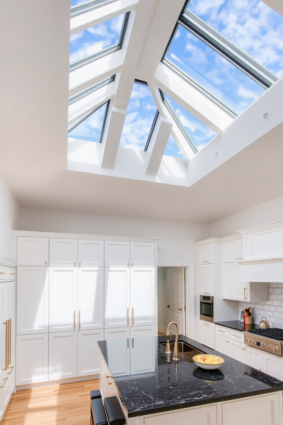 A high ceiling kitchen featuring large skylights that flood the space with natural light. The cabinetry is a sleek white with gold hardware, complemented by a large island topped with a rich dark granite.