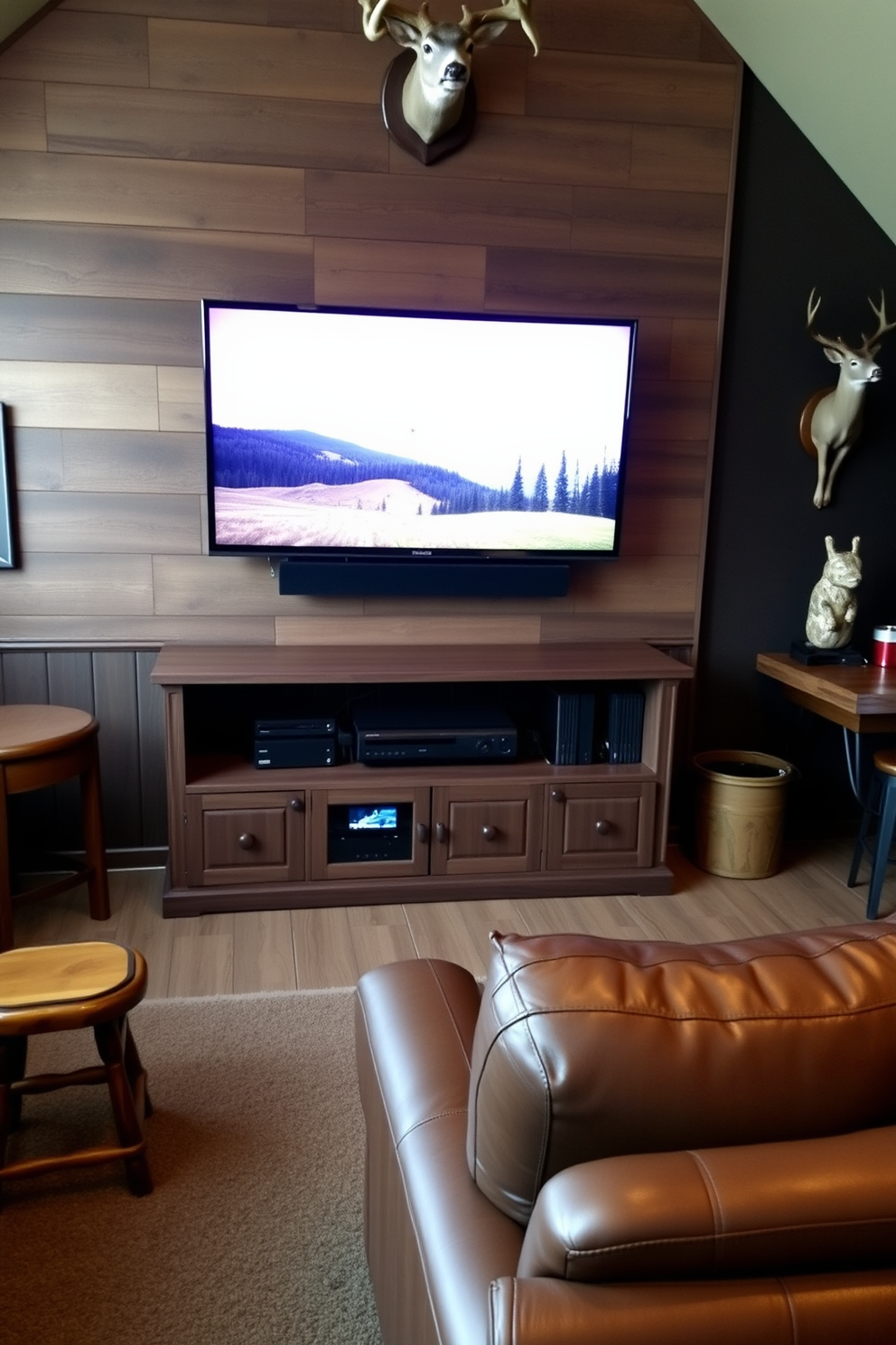 A cozy game console setup featuring a large flat-screen TV mounted on a rustic wooden wall. Below the TV, a sleek media console holds gaming consoles, with comfortable seating arranged for optimal viewing. A hunting-themed man cave designed with dark wood paneling and camouflage accents. The space includes a mounted deer head, a bar area with rustic stools, and a plush leather sofa for relaxation.