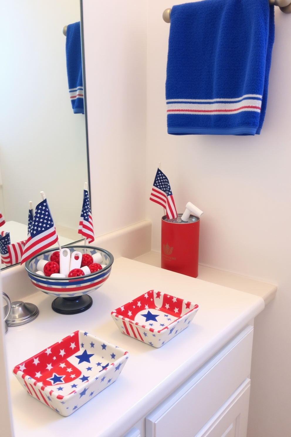 A festive bathroom setting inspired by the Fourth of July. The soap dishes are decorated with red white and blue patterns featuring stars and stripes. The countertop is adorned with a small flag and a decorative bowl filled with themed bath accessories. The walls are painted in a soft white to enhance the patriotic decor while a vibrant blue towel hangs neatly from the rack.