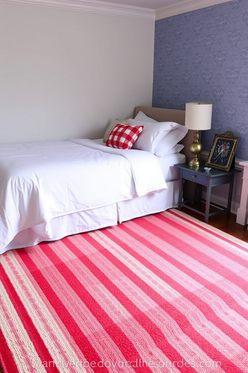 A cozy bedroom featuring a striped area rug in red, white, and blue colors that evoke a patriotic spirit. The rug is placed under a beautifully made bed with crisp white linens and decorative throw pillows in complementary colors. The walls are adorned with subtle star-patterned wallpaper, enhancing the Independence Day theme. A small nightstand holds a vintage lamp and a framed photo of fireworks, creating a festive atmosphere.