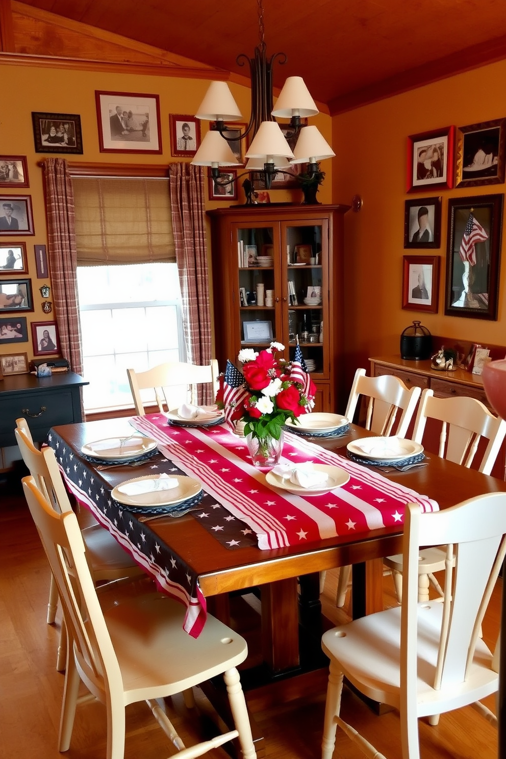 A warm and inviting dining room features a large wooden table surrounded by mismatched chairs, creating a cozy atmosphere. The walls are adorned with a collection of family photos in red, white, and blue frames, celebrating the spirit of Independence Day. A festive table setting includes a vibrant tablecloth with stars and stripes, complemented by simple white dinnerware. Centered on the table is a decorative arrangement of fresh flowers in patriotic colors, enhancing the celebratory theme.