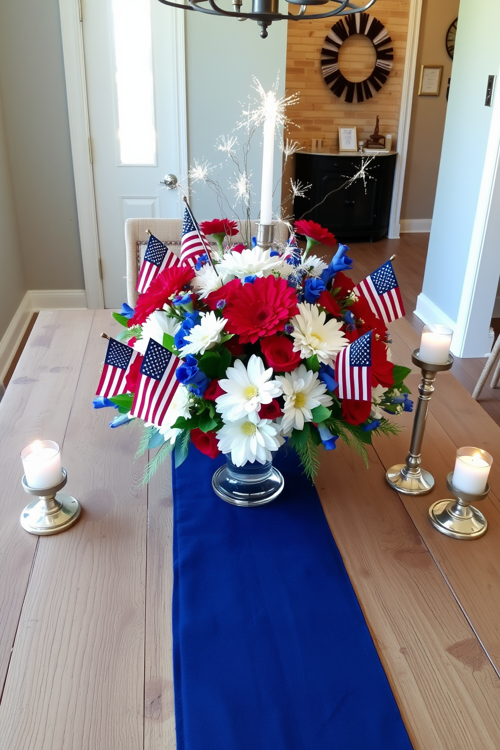 A stunning table centerpiece designed for an Independence Day celebration. The arrangement features vibrant red white and blue flowers mixed with miniature American flags and sparkling fireworks decorations. The centerpiece is placed on a rustic wooden table adorned with a navy blue table runner. Surrounding the centerpiece are elegant candle holders with flickering candles adding a warm glow to the entryway.