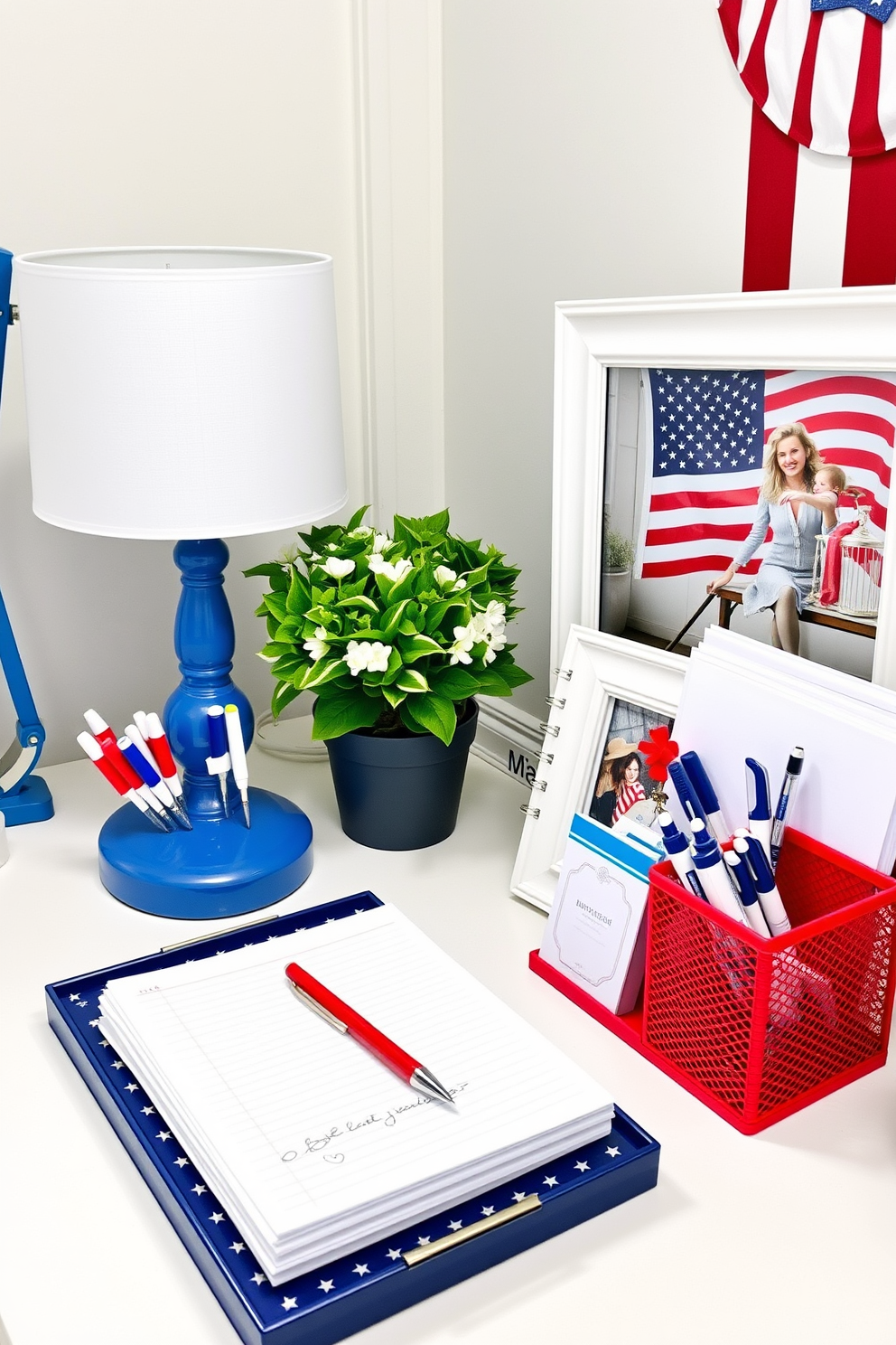 A stylish home office decorated for Independence Day with red white and blue desk accessories. The desk features a vibrant red organizer filled with pens and notepads alongside a blue desk lamp and a white picture frame displaying a patriotic photo.