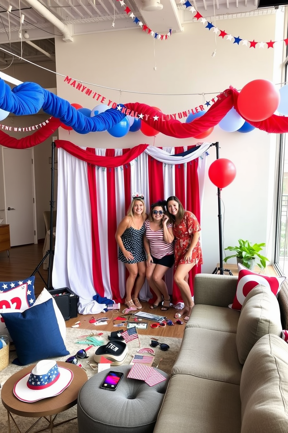 A creative photo booth is set up with a backdrop featuring red white and blue colors and stars. Various props including hats sunglasses and flags are scattered around for guests to use during the celebration. The loft is decorated with festive garlands and balloons in patriotic colors. Comfortable seating areas are arranged to encourage socializing and fun photo opportunities.