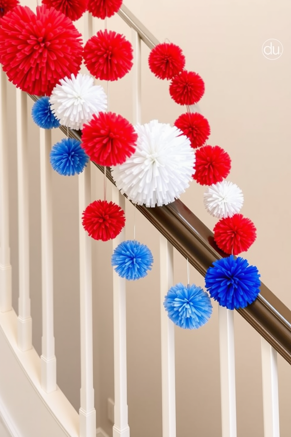 Hanging vibrant red white and blue pom poms adorn the staircase railing creating a festive atmosphere for Independence Day celebrations. The pom poms are strategically placed at varying heights to add depth and visual interest to the overall decoration.