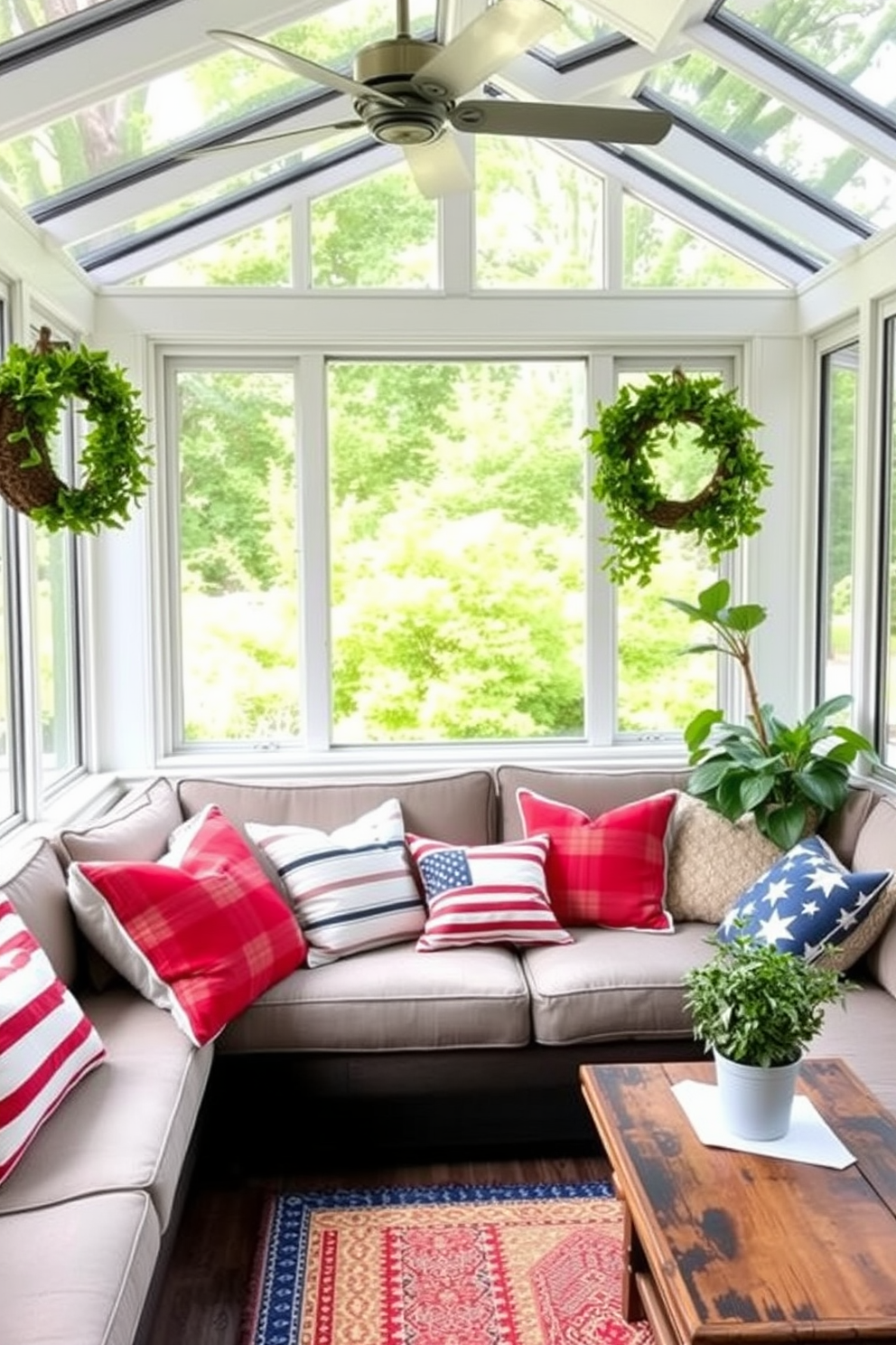 Red white and blue throw pillows are arranged on a comfortable sectional sofa in a bright sunroom. The pillows feature various patterns including stripes and stars, adding a festive touch to the space. The sunroom is filled with natural light from large windows adorned with sheer white curtains. Potted plants and patriotic decorations enhance the cheerful atmosphere, celebrating Independence Day in style.