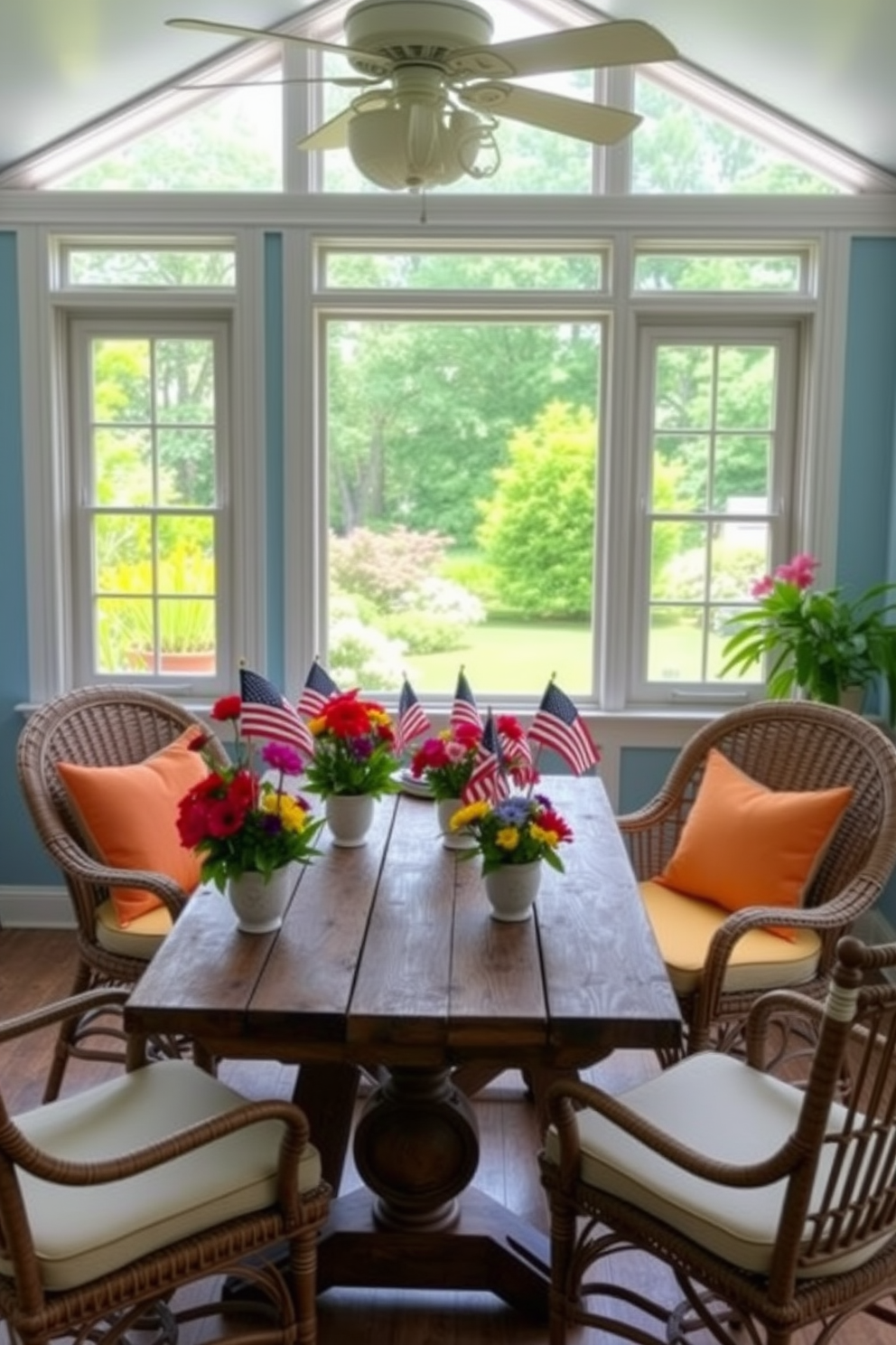 A vibrant sunroom filled with natural light features a large window showcasing a beautiful garden outside. In the center of the room, a rustic wooden table is adorned with miniature flags inserted into colorful flower arrangements, celebrating Independence Day. Surrounding the table are comfortable wicker chairs with bright cushions, creating a cozy atmosphere. The walls are painted in a soft blue hue, enhancing the cheerful decor and inviting a sense of relaxation.