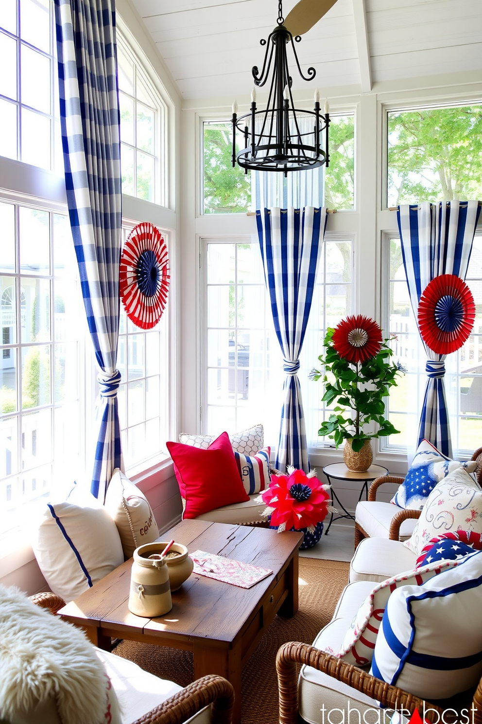 A bright and airy sunroom filled with natural light. The windows are adorned with blue and white striped curtains that gently sway in the breeze. Cozy seating arrangements feature a mix of plush cushions and a rustic wooden coffee table. Red, white, and blue decorative accents celebrate Independence Day throughout the space.