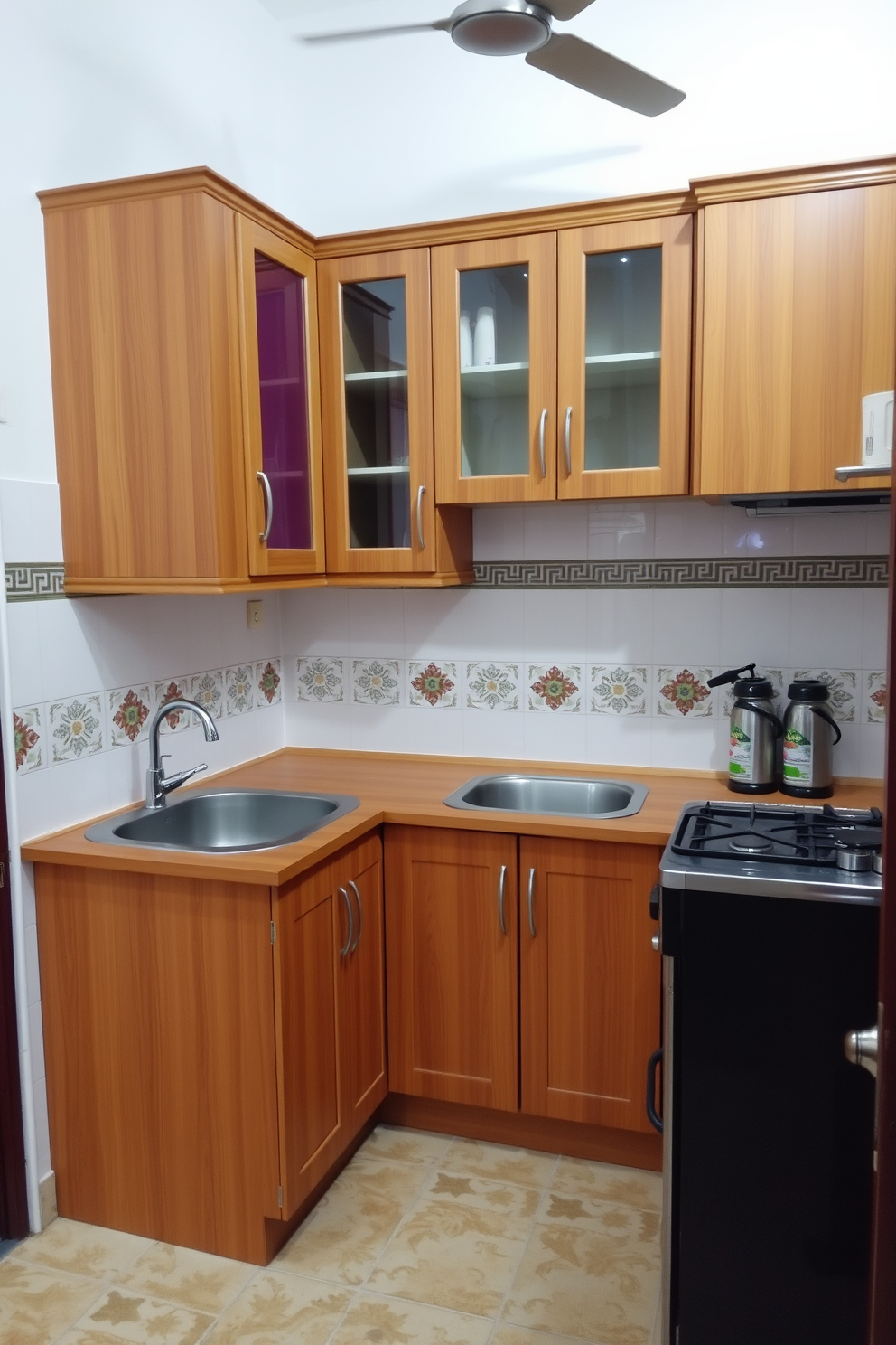 A cozy Indian kitchen featuring a compact layout. The space includes a modular wooden cabinet with vibrant colored doors and a small island that doubles as a dining area. The walls are adorned with traditional Indian tiles, adding a pop of color. A stainless steel sink and a built-in stove maximize functionality while maintaining an inviting atmosphere.