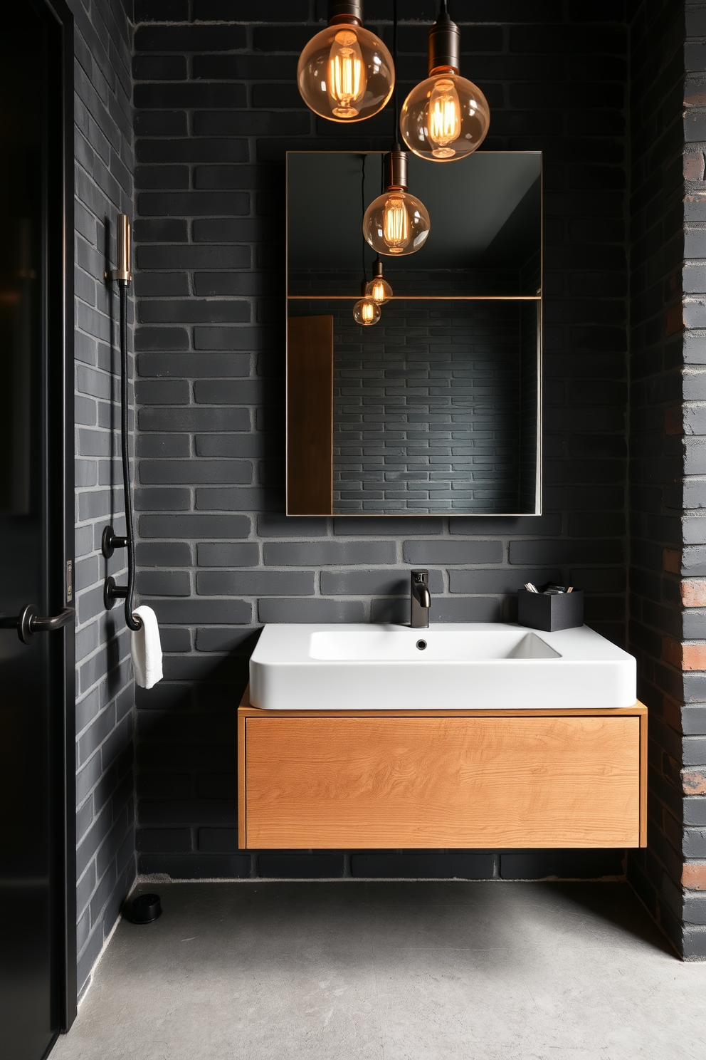 A modern industrial bathroom featuring wall-mounted faucets that enhance the space-saving design. The walls are exposed brick with a matte black finish, and the floor is polished concrete with a matte texture. A large mirror with a thin metal frame is positioned above a sleek, floating vanity made of reclaimed wood. Industrial-style pendant lights hang from the ceiling, casting a warm glow over the space.