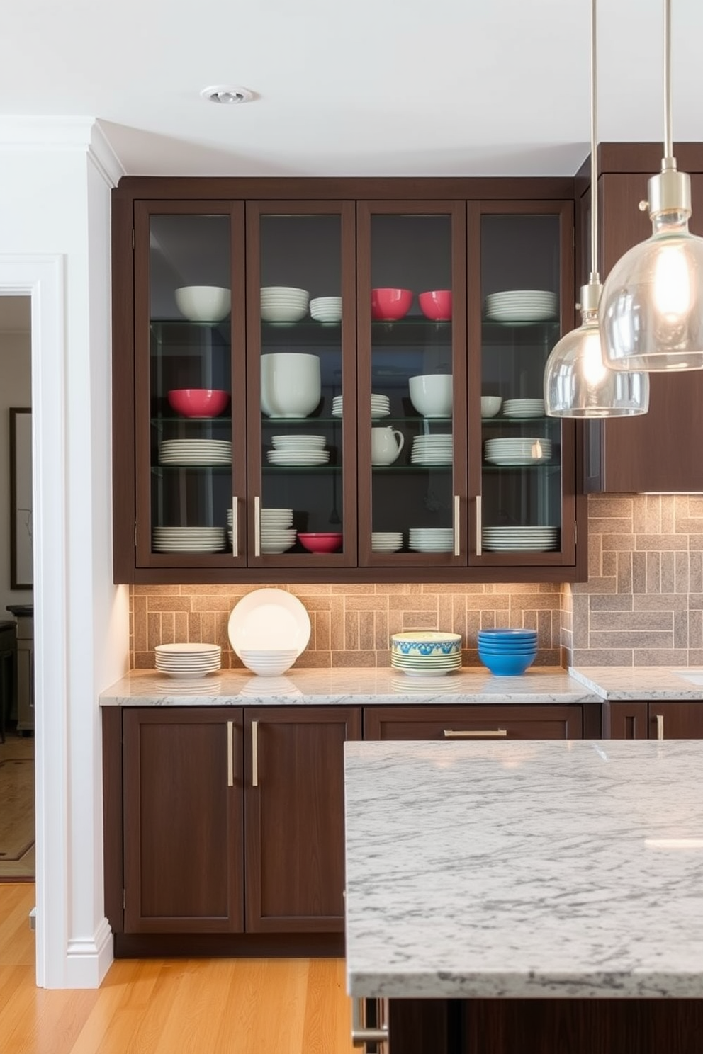 A modern kitchen featuring glass-front cabinets that elegantly showcase an array of colorful dishware. The cabinets are framed with sleek stainless steel hardware, complementing the minimalist design of the space. The kitchen island is topped with a polished granite surface, providing ample space for meal preparation and casual dining. Pendant lights hang above the island, casting a warm glow that enhances the inviting atmosphere of the room.