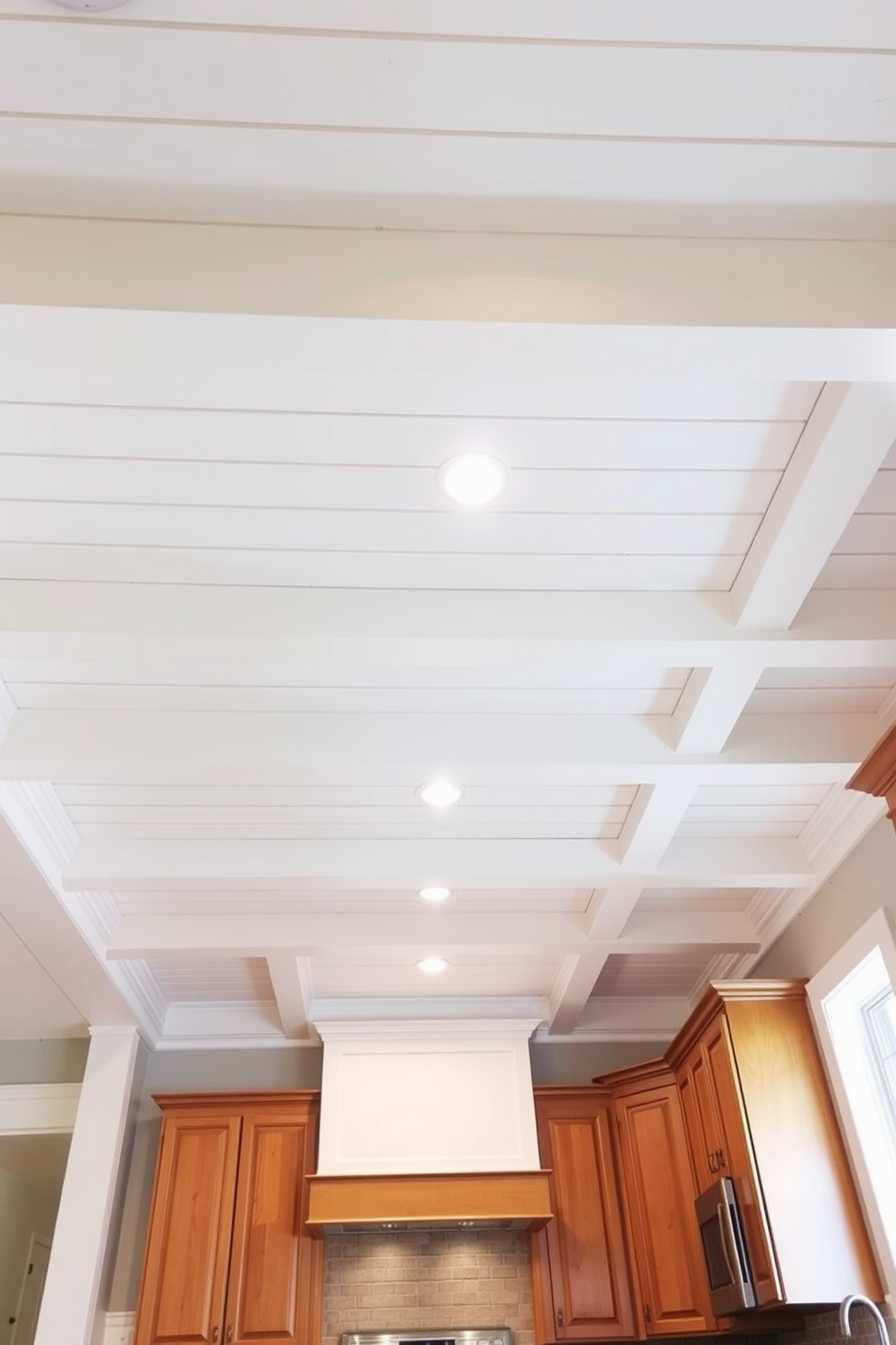 A stunning kitchen ceiling features painted wooden beams that add depth and character to the space. The beams are painted in a soft white color, creating a bright and airy atmosphere while contrasting beautifully with the warm wood cabinetry below. The ceiling design incorporates recessed lighting fixtures that enhance the overall ambiance. A subtle coffered pattern is created with the beams, adding an elegant touch to this modern kitchen design.