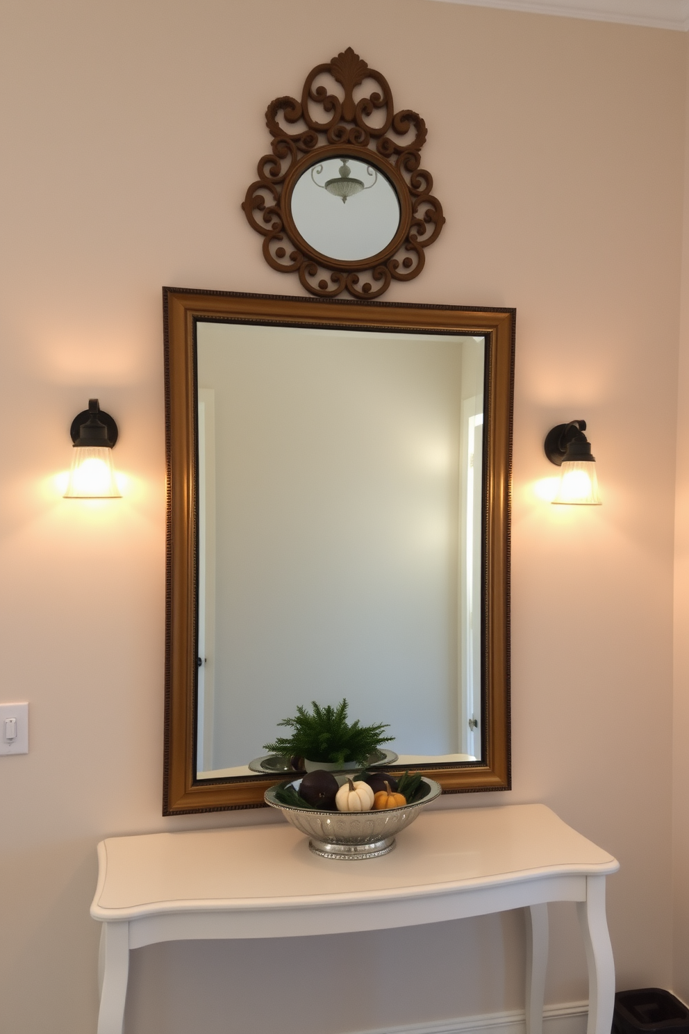 A welcoming entryway features a large mirror with an ornate decorative frame that adds a touch of elegance. Flanking the mirror are two stylish sconces that provide warm lighting, creating an inviting atmosphere. The walls are painted in a soft neutral tone, complemented by a chic console table beneath the mirror. On the table, a decorative bowl holds seasonal accents, while a small potted plant adds a splash of greenery.