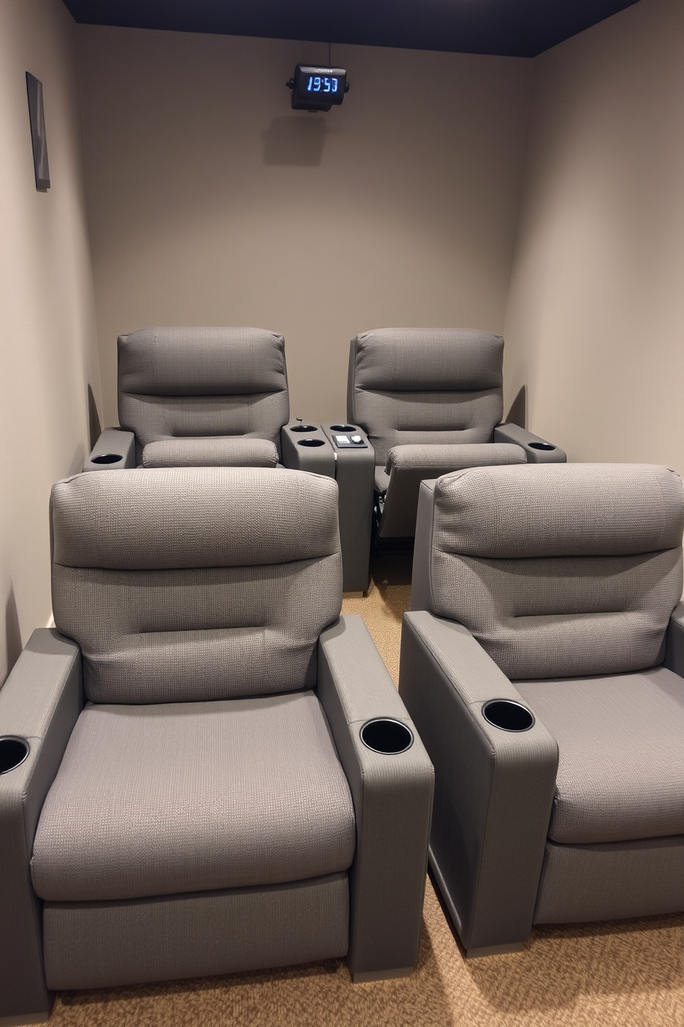 A cozy home theater setup featuring comfortable reclining chairs arranged for optimal viewing. The chairs are upholstered in a soft gray fabric, with built-in cup holders and adjustable headrests for maximum relaxation.