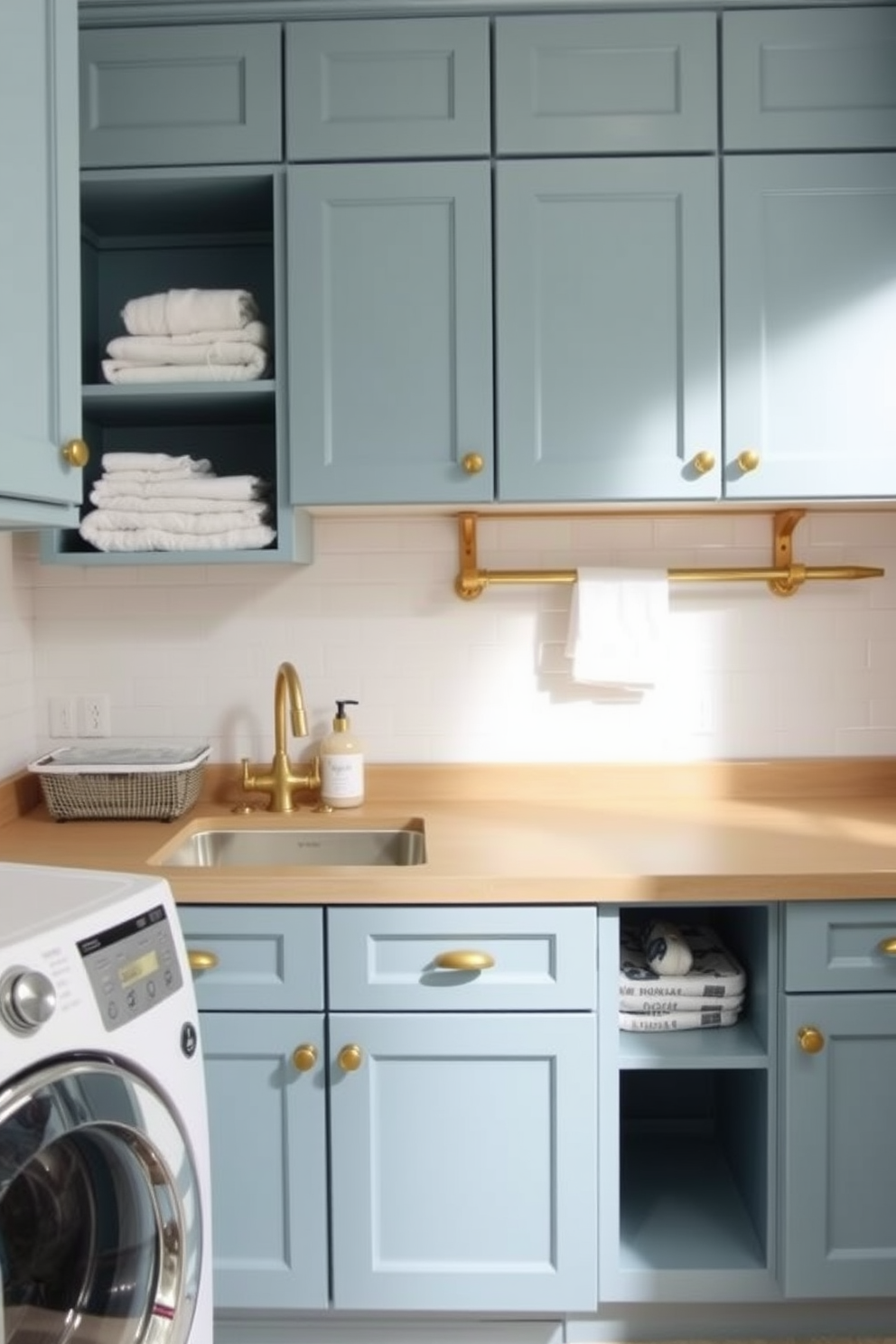 A practical laundry room design features a spacious countertop for folding clothes, with a deep sink installed for convenience. The cabinetry is painted in a soft blue hue, complemented by brass hardware and open shelving displaying neatly folded towels and laundry supplies.