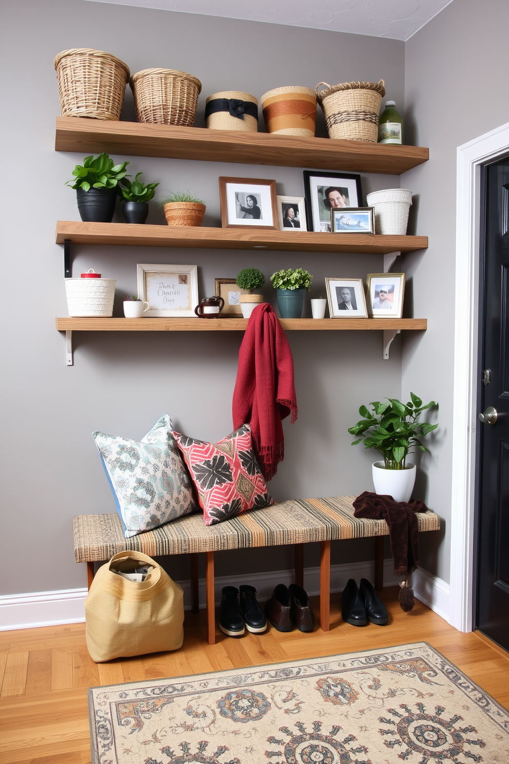 A cozy mudroom featuring floating shelves adorned with various display items. The shelves are made of reclaimed wood and hold a mix of decorative baskets, potted plants, and framed photos, creating an inviting atmosphere. The walls are painted in a soft gray hue, complemented by a stylish bench with colorful cushions. A patterned rug lies beneath, adding warmth and character to the space while providing a functional area for shoes and bags.