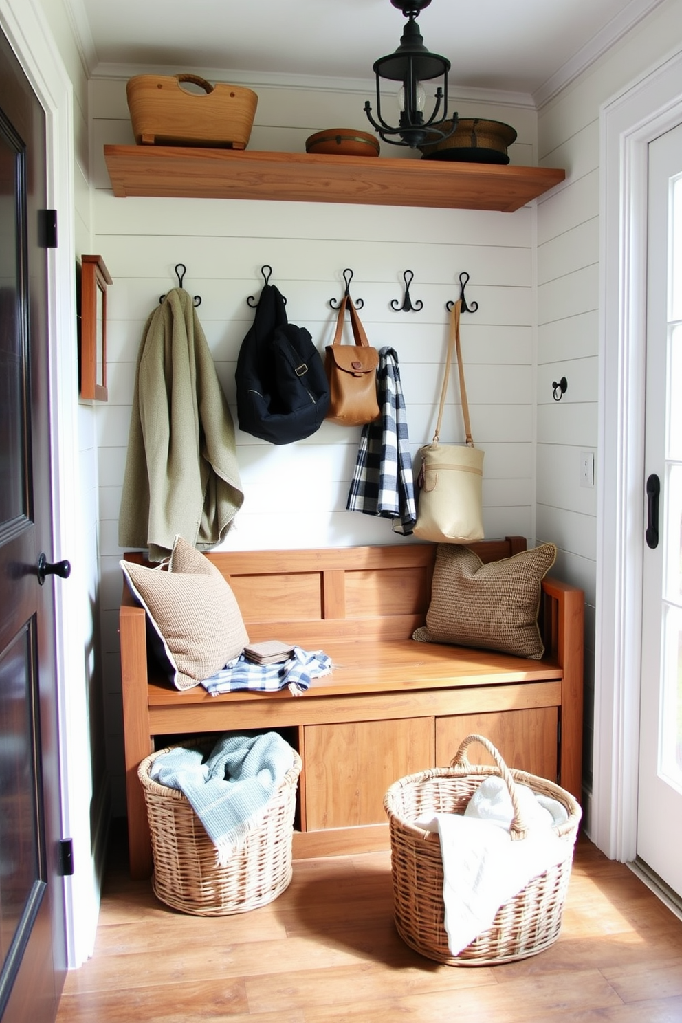 A cozy mudroom featuring rustic elements that evoke a farmhouse feel. The space includes a wooden bench with storage underneath, surrounded by shiplap walls painted in a soft white color. Hanging above the bench are vintage hooks for coats and bags, made from wrought iron. A woven basket sits on the floor, filled with blankets, while a large window allows natural light to flood the room.