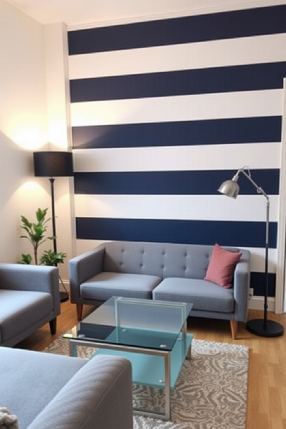 A cozy living room featuring an accent wall adorned with bold striped wallpaper in shades of navy and white. The room is furnished with a plush gray sofa and a sleek glass coffee table, creating a modern yet inviting atmosphere. In the corner, a small potted plant adds a touch of greenery, while a stylish floor lamp illuminates the space. The overall design emphasizes clever use of space, making it ideal for small living areas while maintaining a chic aesthetic.