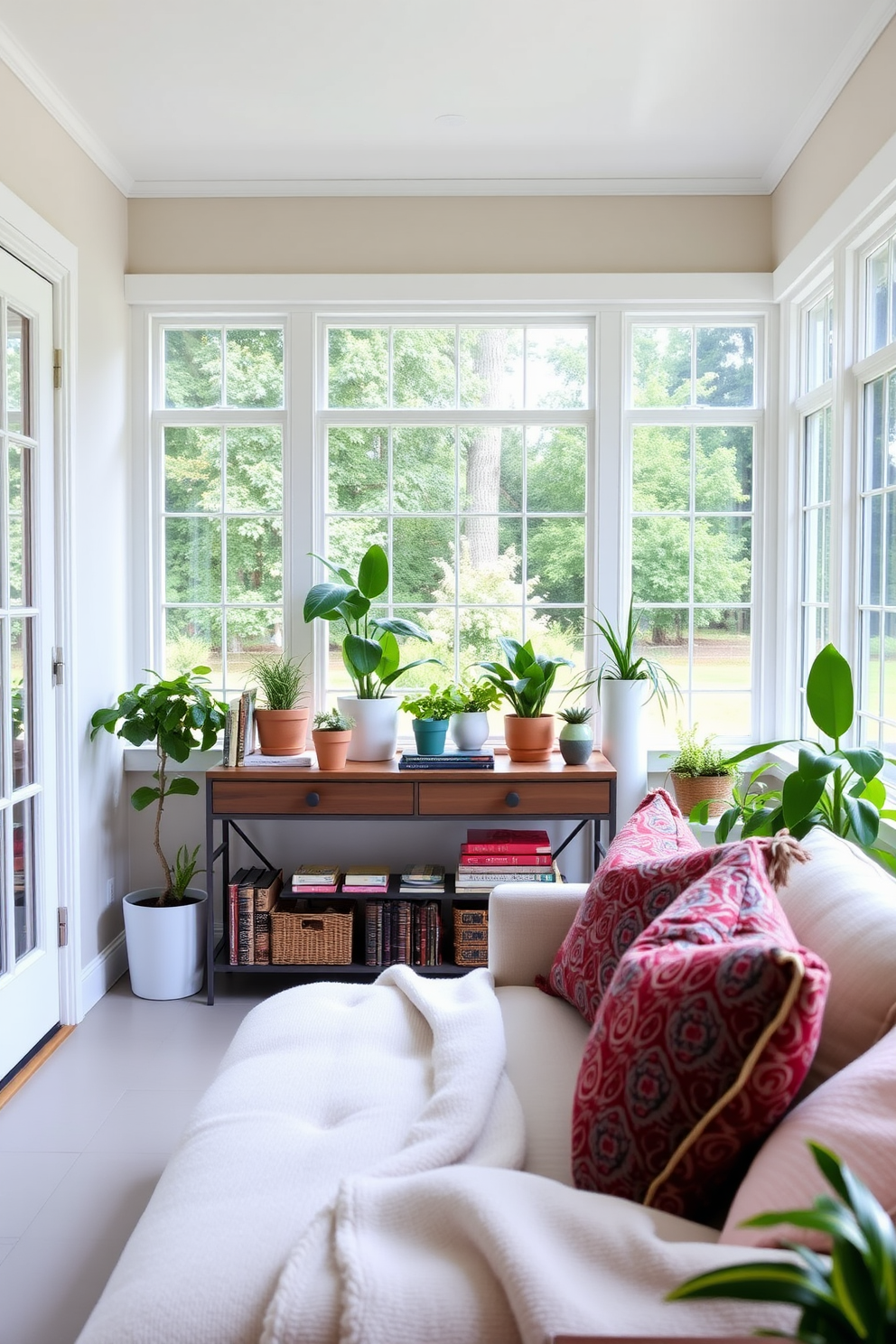 A bright and inviting sunroom features a stylish console table positioned against the wall, adorned with a collection of potted plants and decorative books. Large windows allow natural light to flood the space, enhancing the cozy seating area with plush cushions and a soft throw blanket.