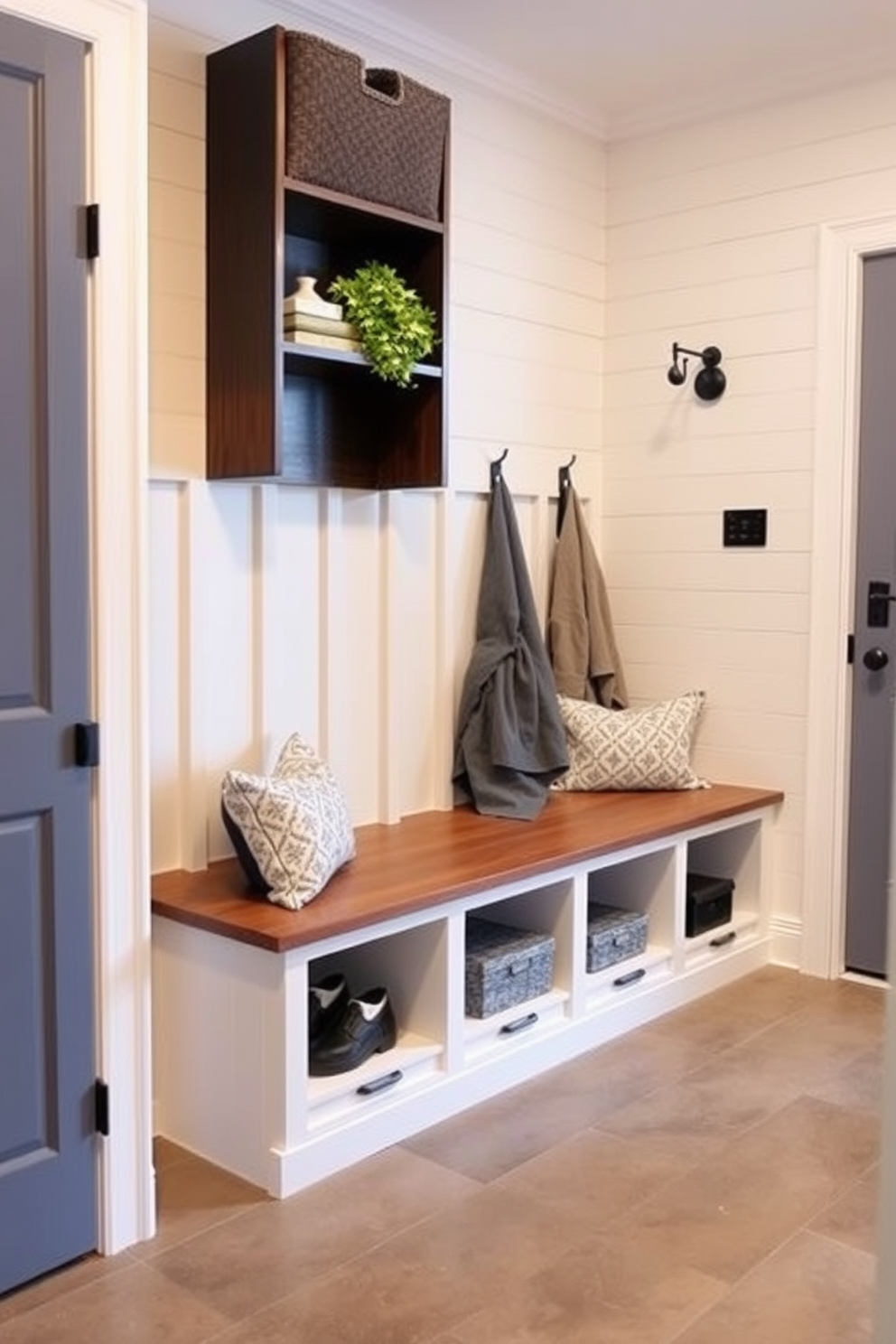 A spacious mudroom features a built-in bench with hidden storage compartments beneath. The walls are adorned with shiplap, and the floor is covered in durable ceramic tiles for easy maintenance.